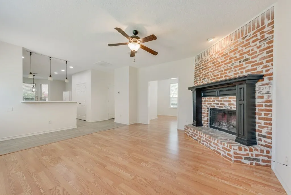 Living area featuring wood-finish flooring, a brick fireplace with a dark wood mantel, a ceiling fan with integrated lighting, and recessed ceiling lighting