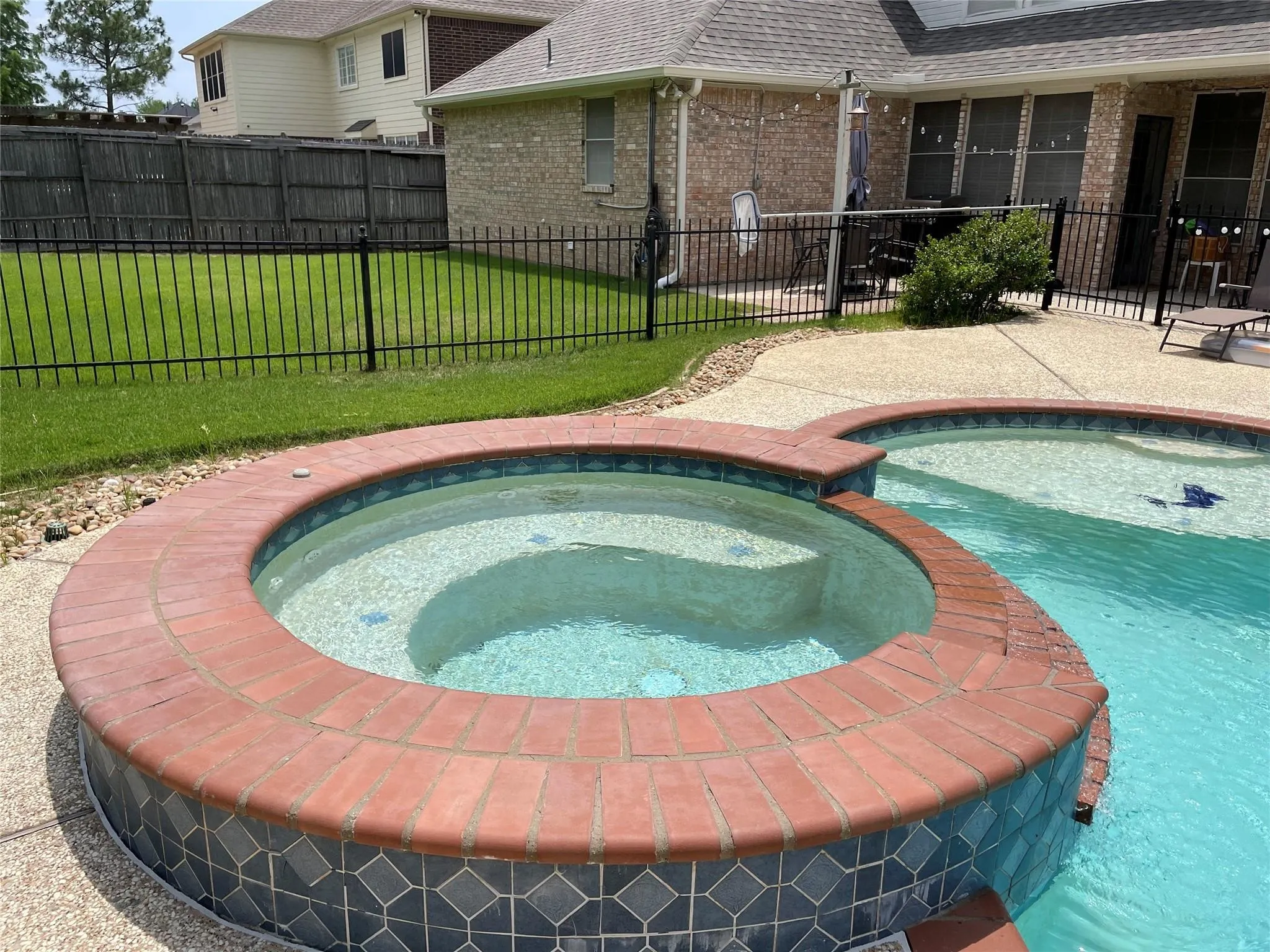 Brick-edged spa with integrated steps and patterned tile surround