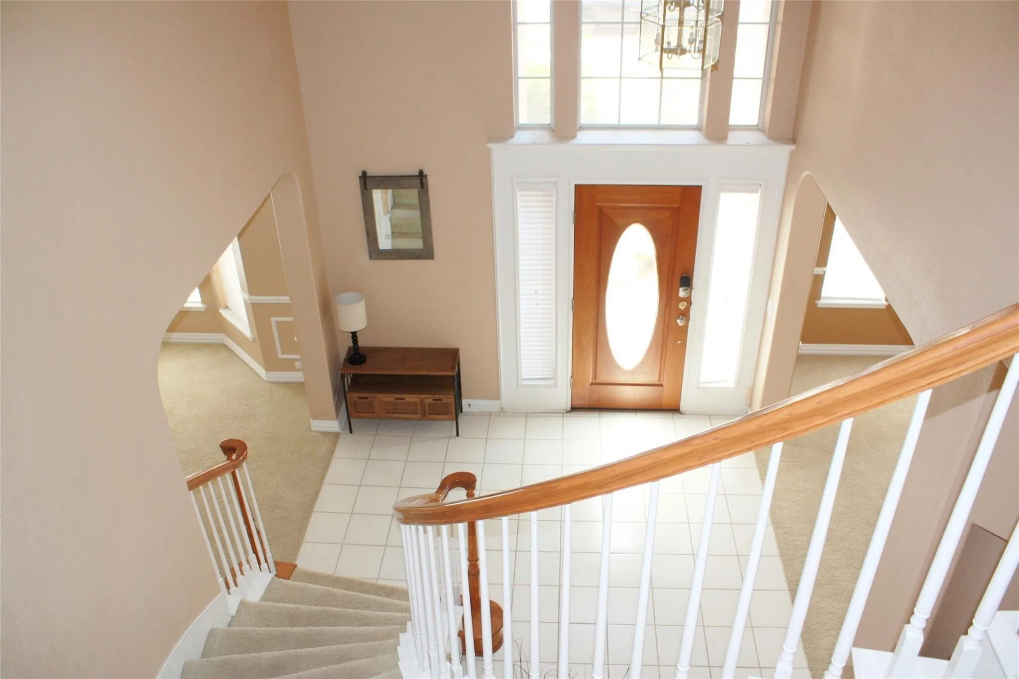 Two-story entryway featuring tile flooring, a prominent wooden door with an oval glass insert, and sidelight windows