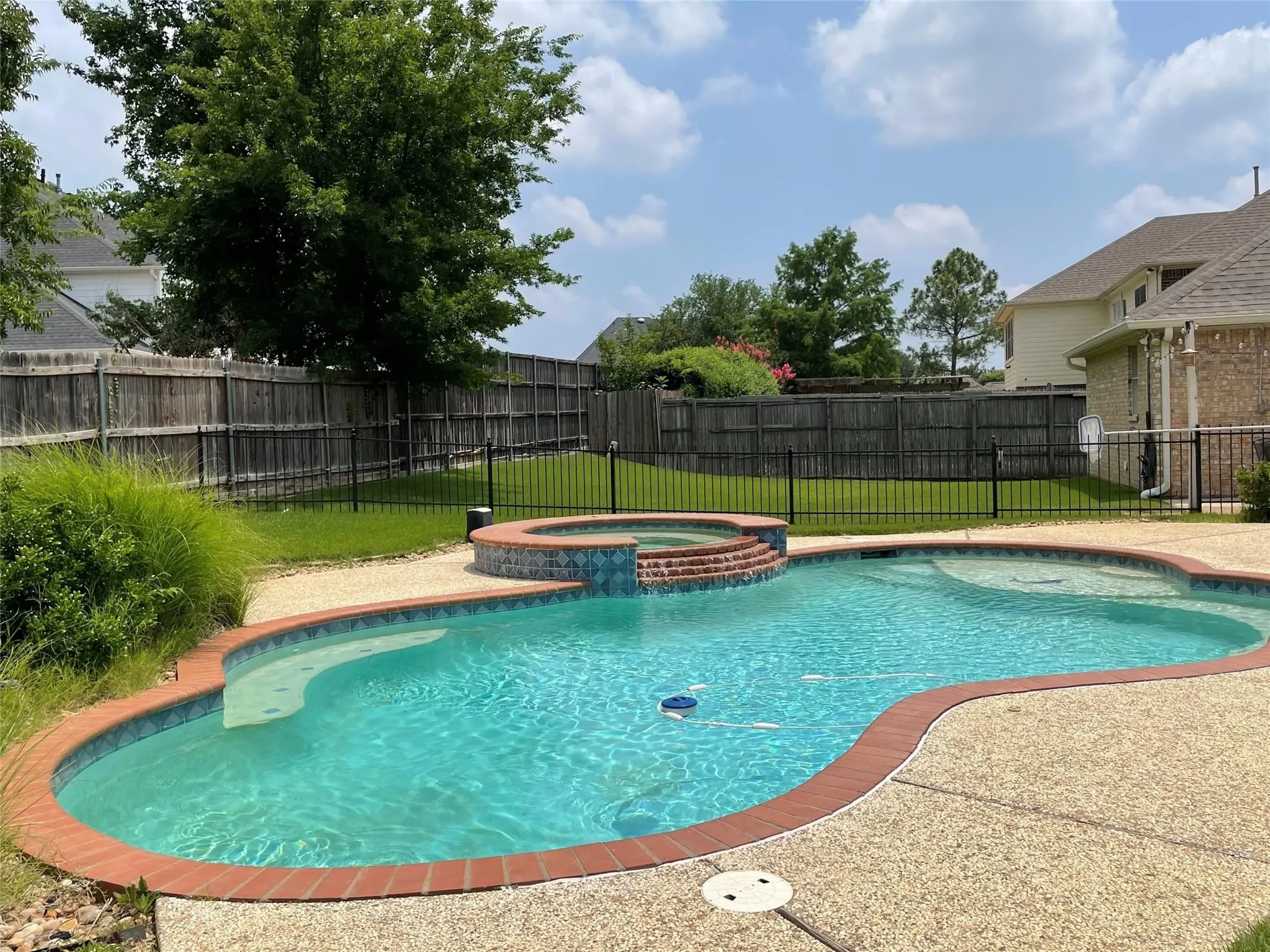 Freeform swimming pool with integrated spa and decorative tile
