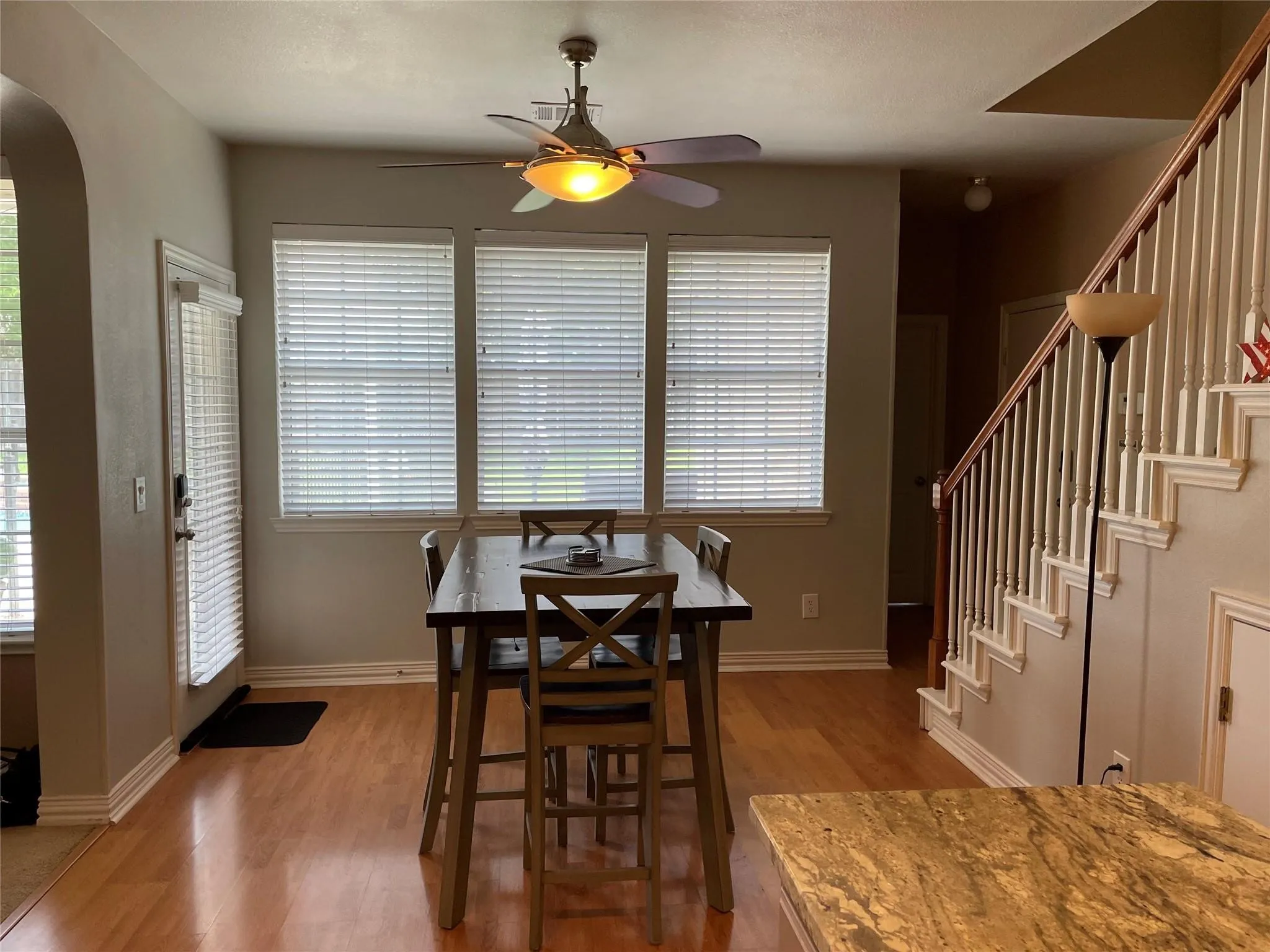 Wood-finish flooring throughout the space, with a ceiling fan with integrated lighting