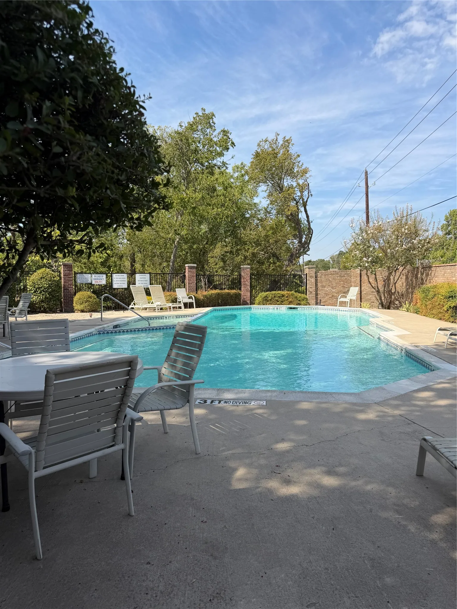 Outdoor swimming pool with a concrete surround and perimeter fencing