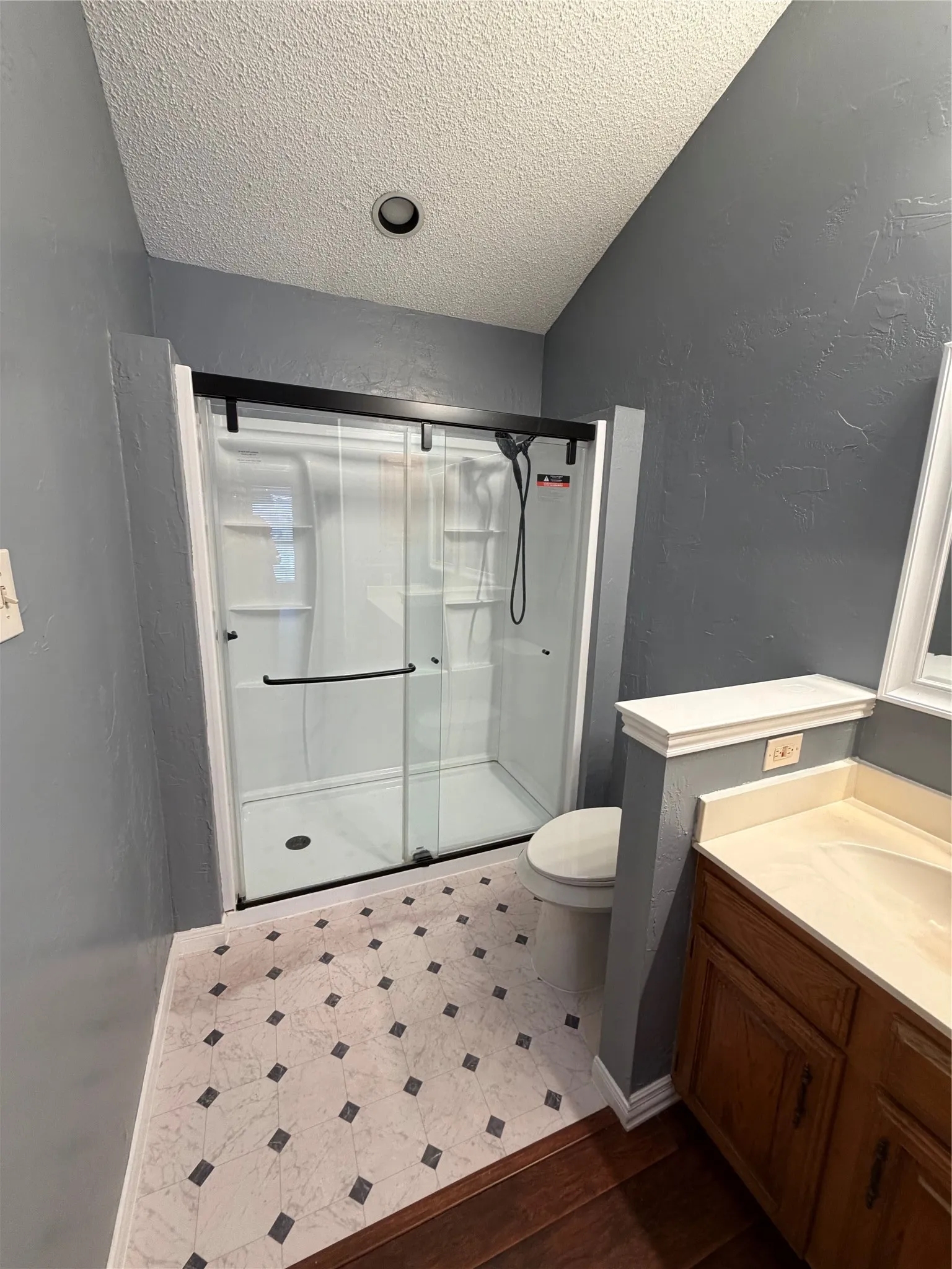 Shower enclosure with black-framed sliding glass doors, integrated shower system, and recessed lighting