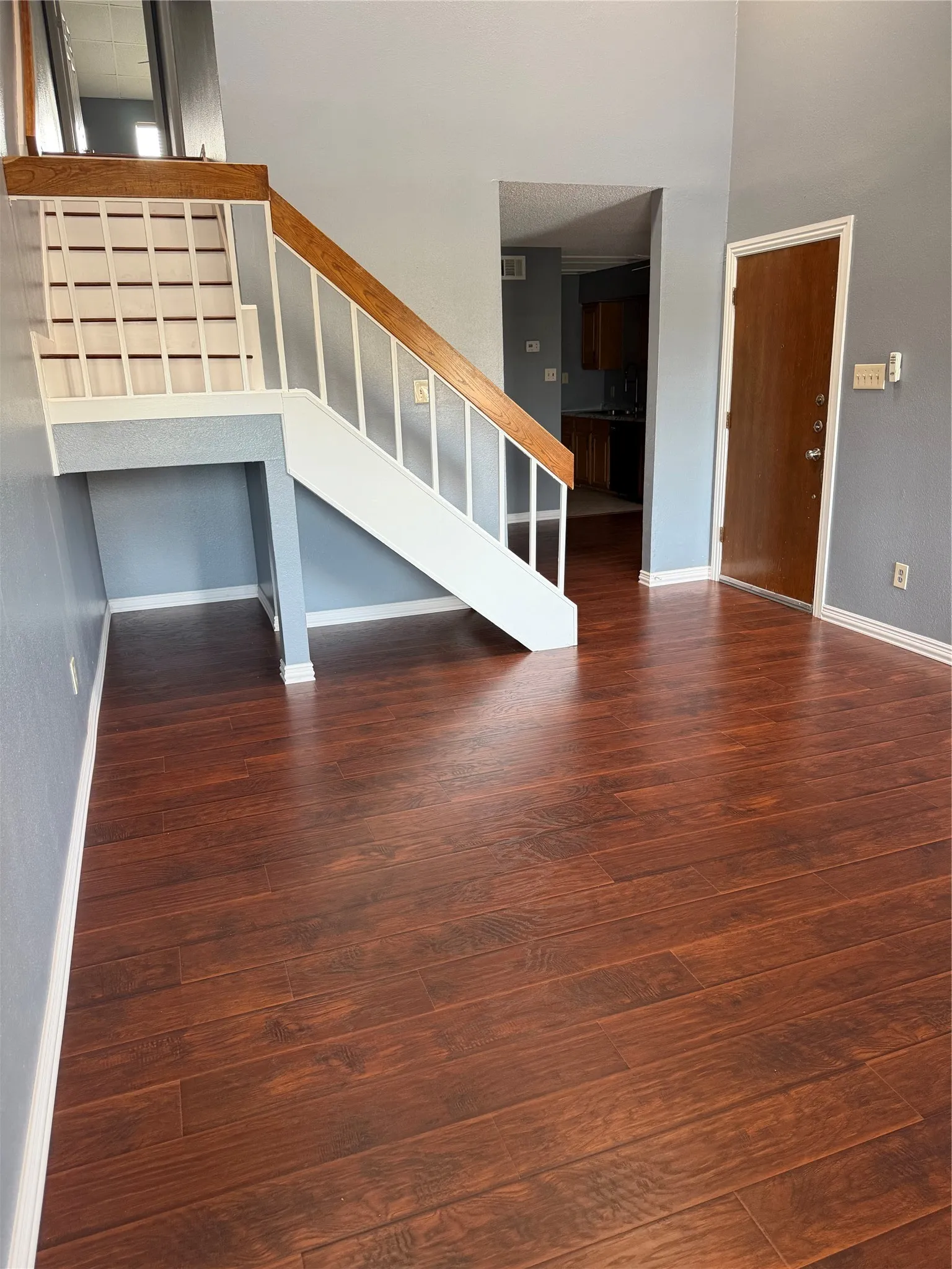 Wood-finish flooring throughout, with a painted staircase featuring a wood handrail and white balusters