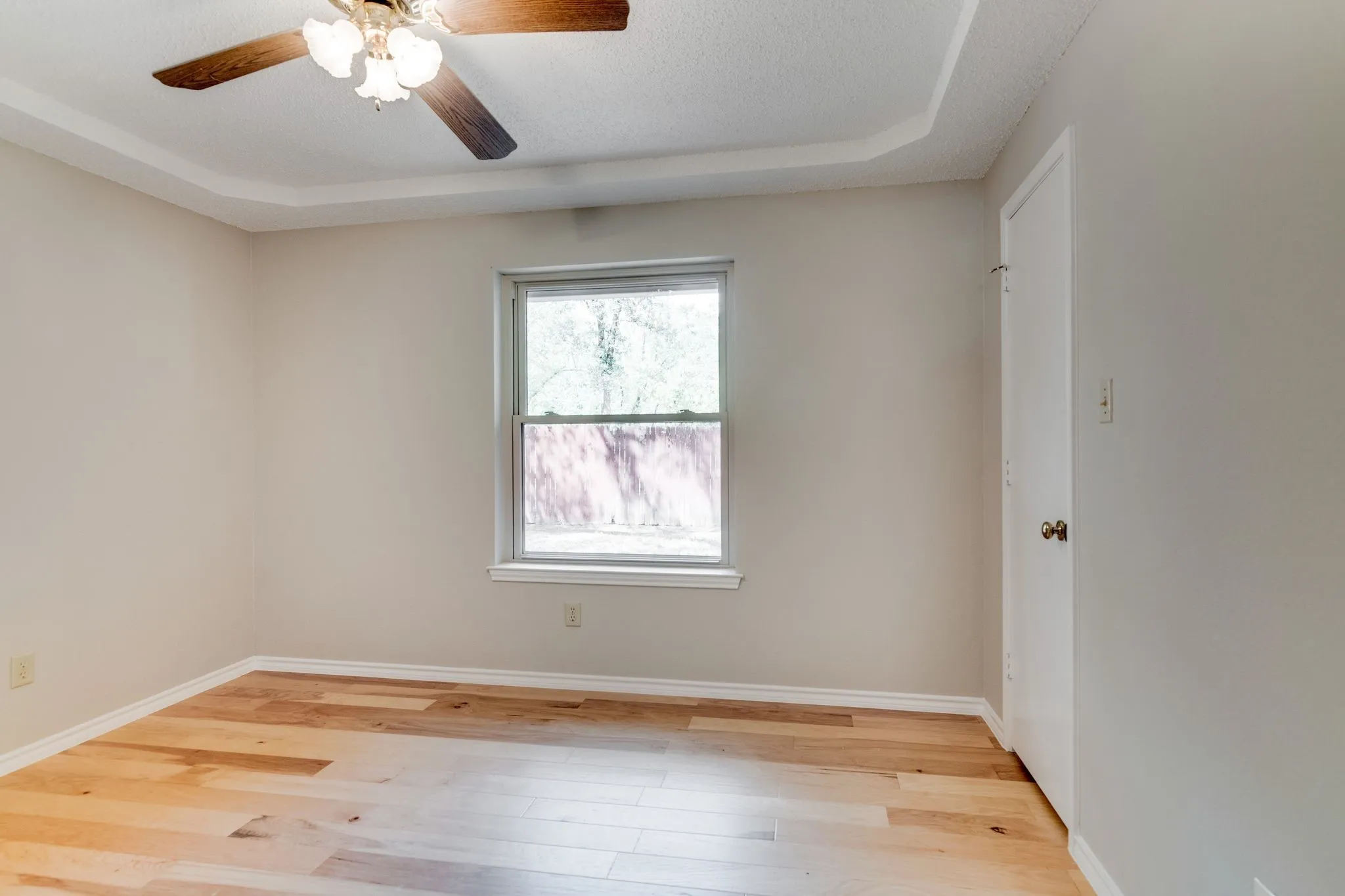 Secondary bedroom at the back of house overlooks backyard and has walk in closet with wood flooring