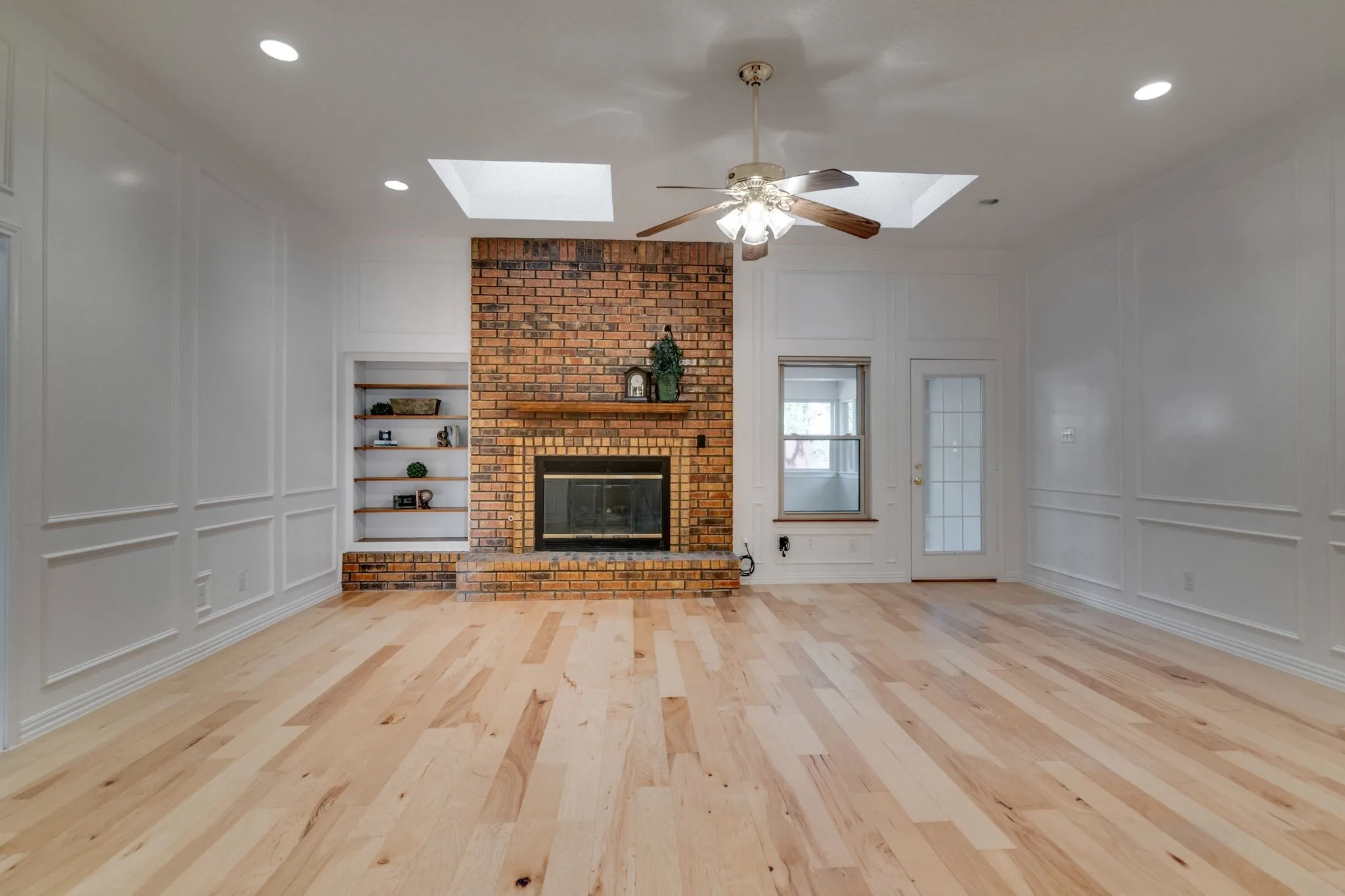 Beautiful focal point with brick fireplace & built in book shelves.  Picture frame paneling adds upgraded feel to the room!