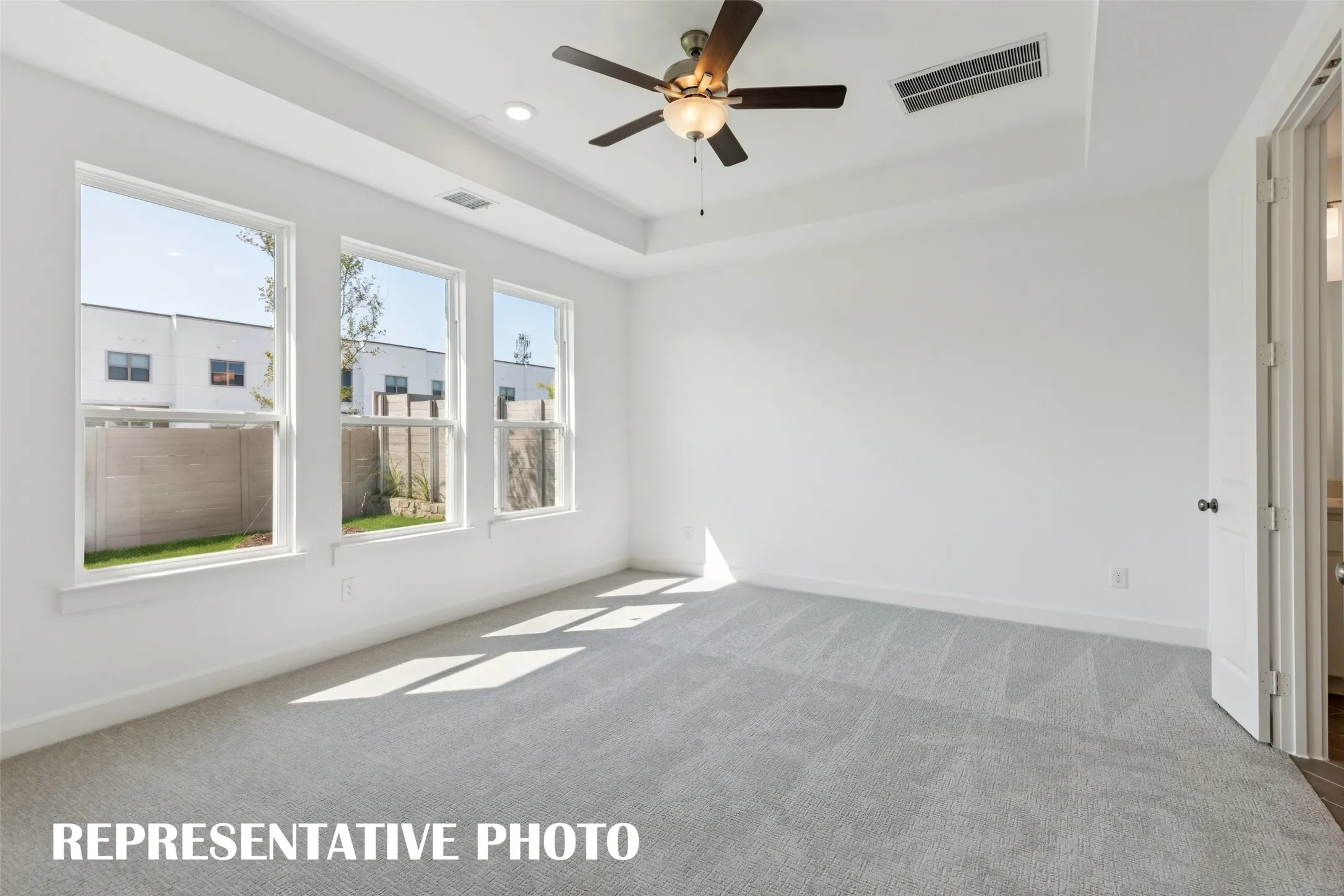High ceilings, plush carpet and a wall of windows create a peaceful and relaxing owner's suite.  REPRESENTATIVE