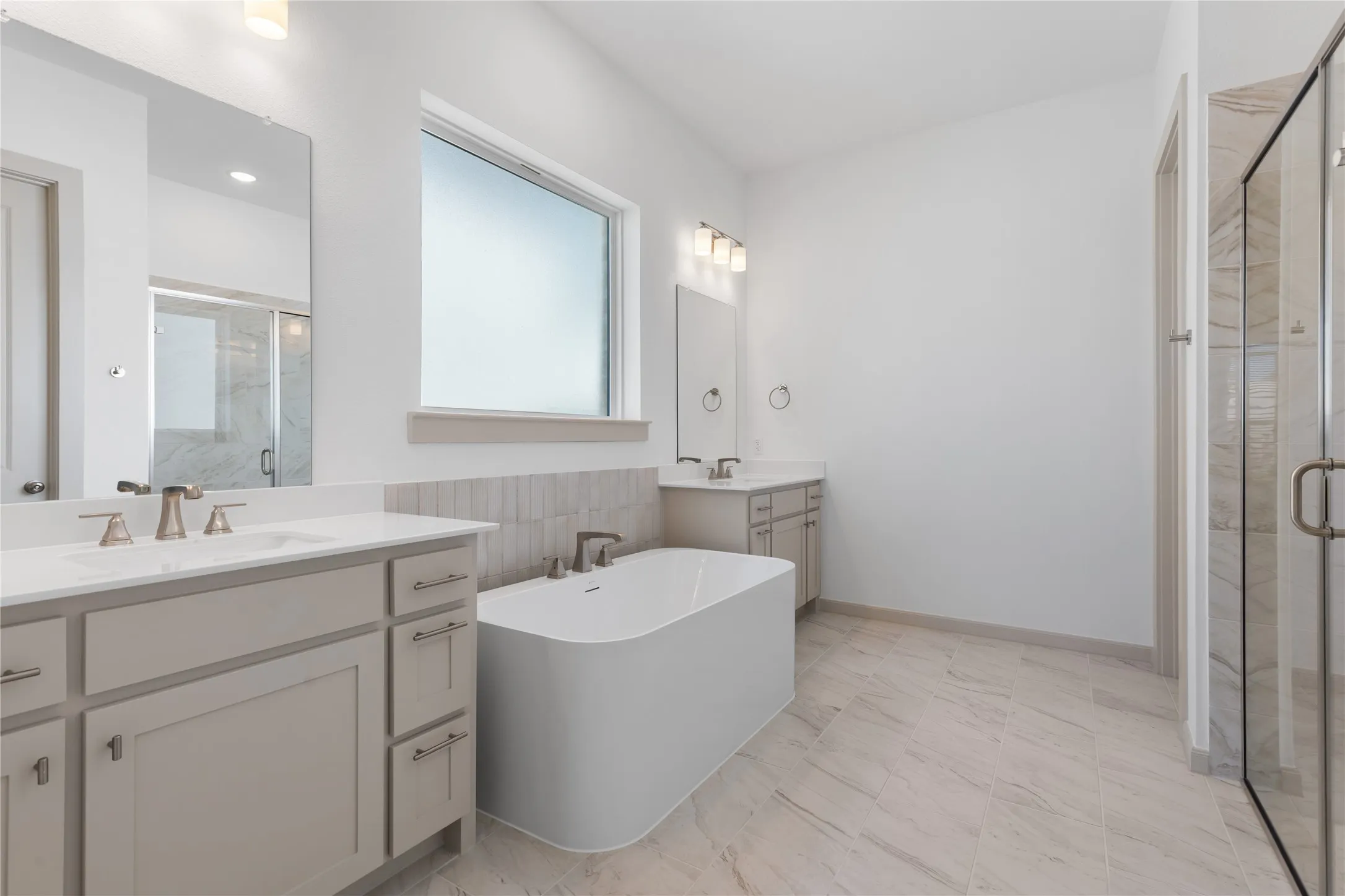 Dual vanities with quartz countertops, a freestanding soaking tub, a large window, a glass-enclosed shower, and tile flooring
