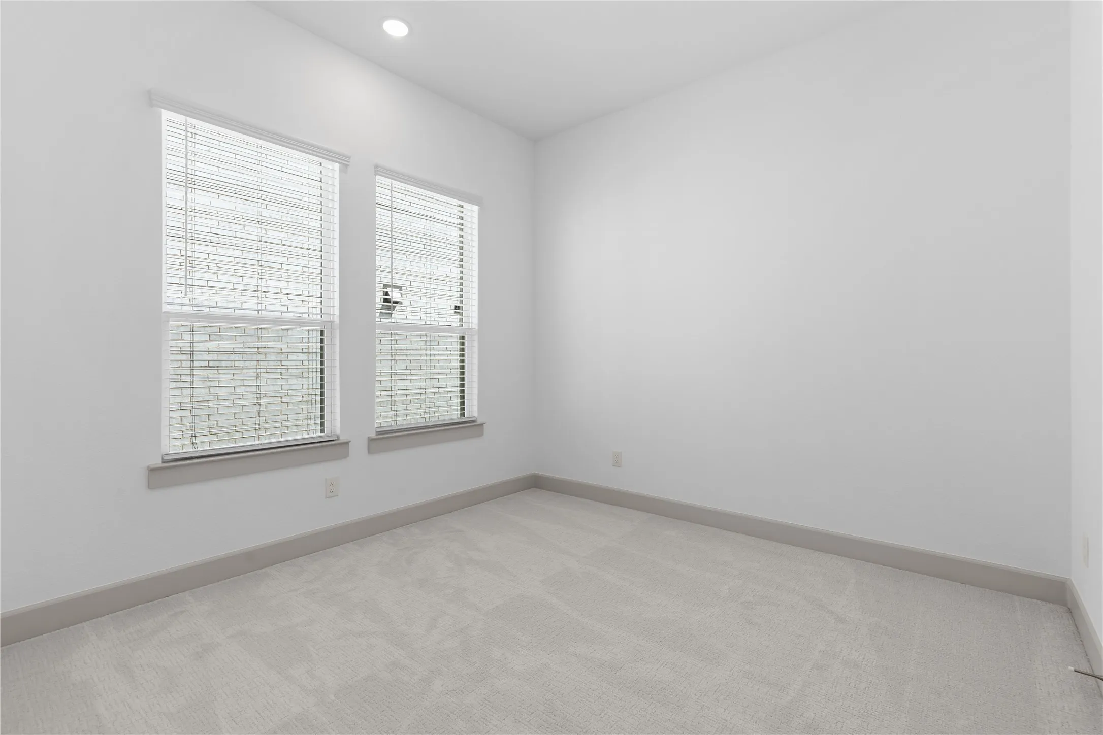 White walls, recessed lighting, and light-toned carpeting