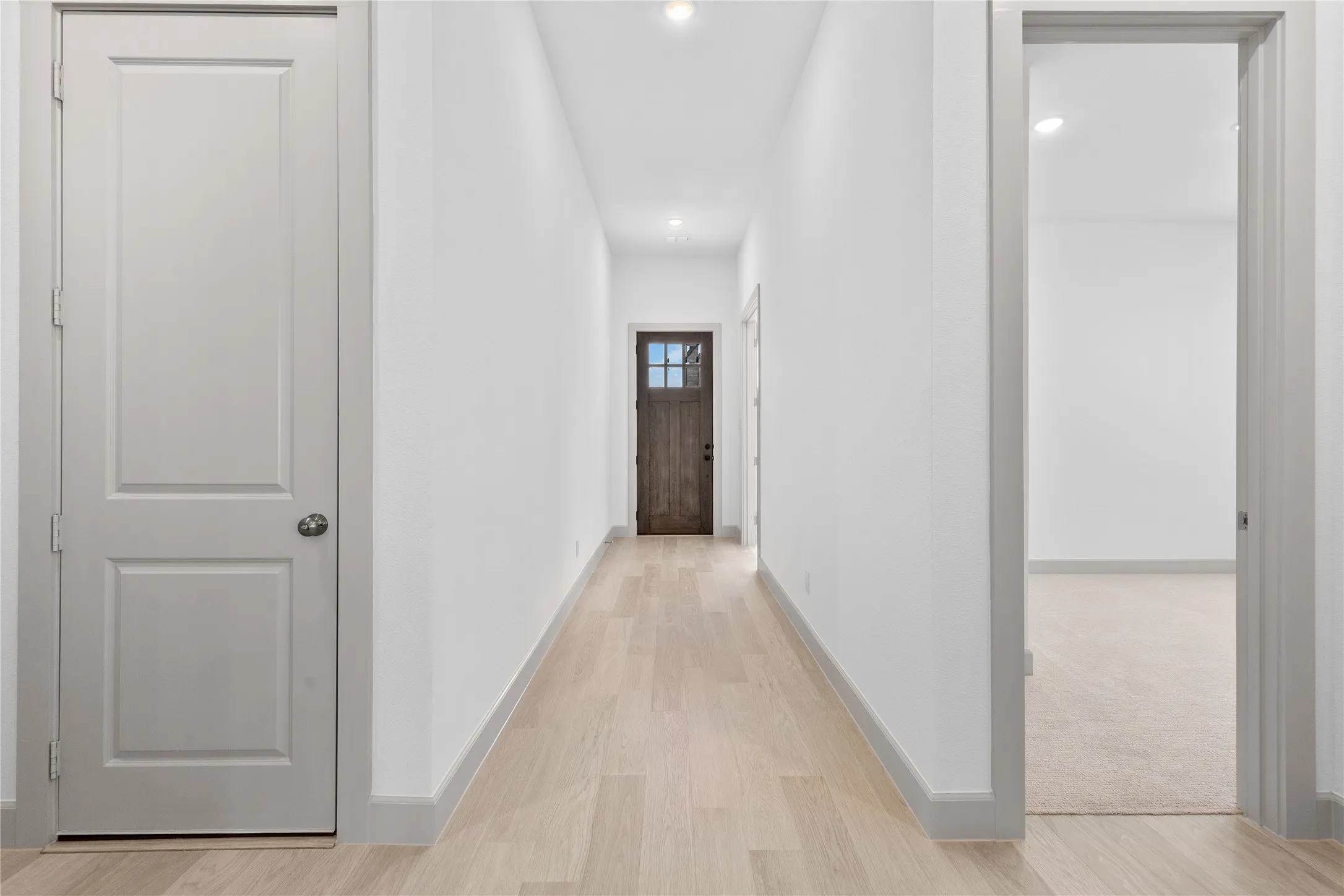 Hallway featuring light wood-finish flooring, recessed lighting, and a paneled entry door