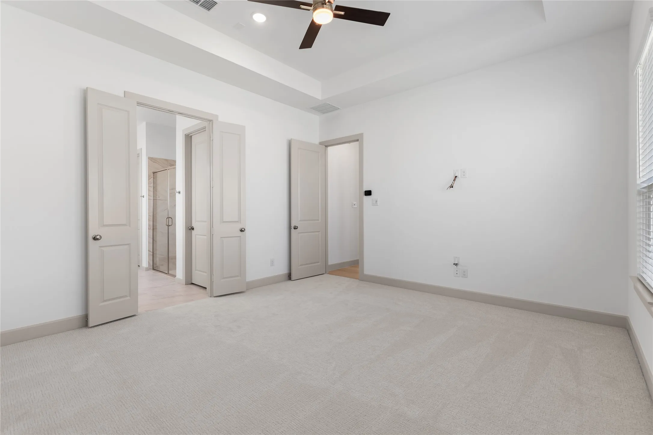 Tray ceiling with a ceiling fan, light-toned carpeting, white walls, and a window with blinds