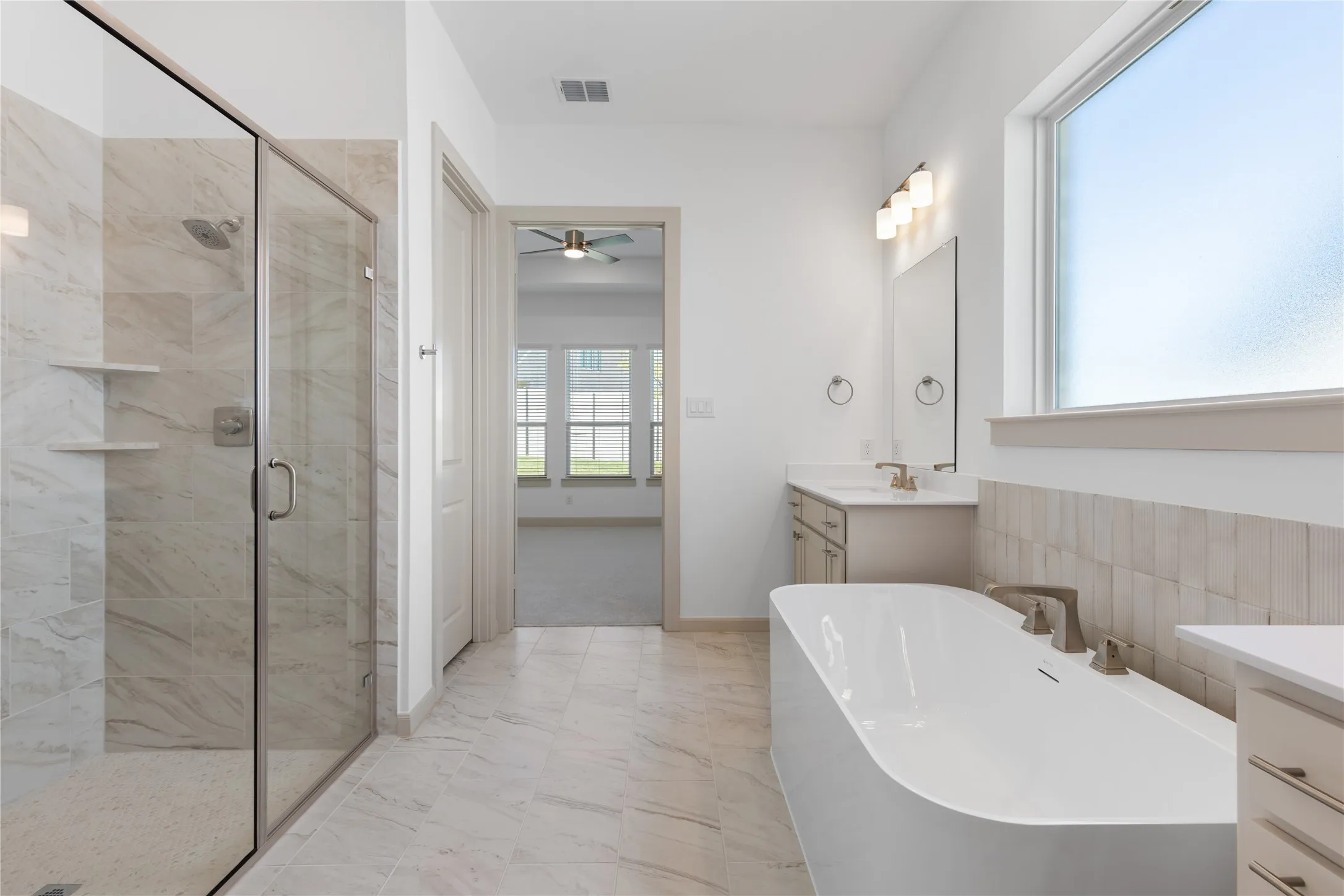 Contemporary bathroom featuring a freestanding soaking tub, glass-enclosed shower with built-in shelving, dual vanity with undermount sinks, and large format tile flooring