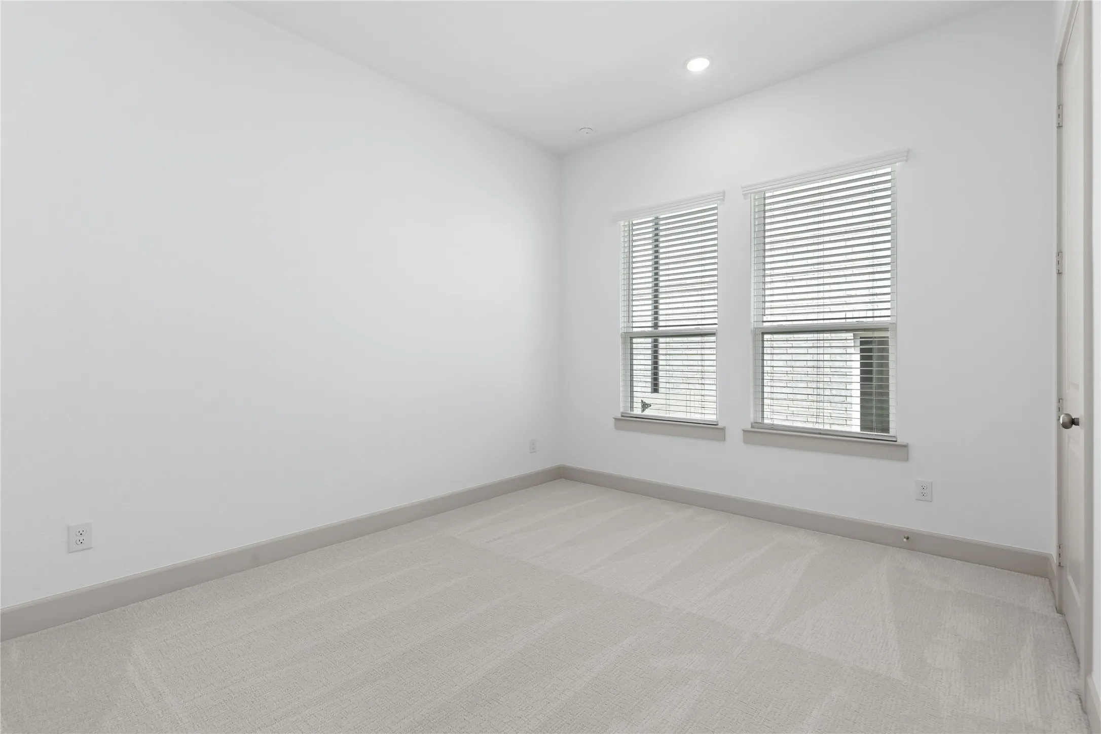 Recessed lighting, wall-to-wall carpeting, and two windows with blinds