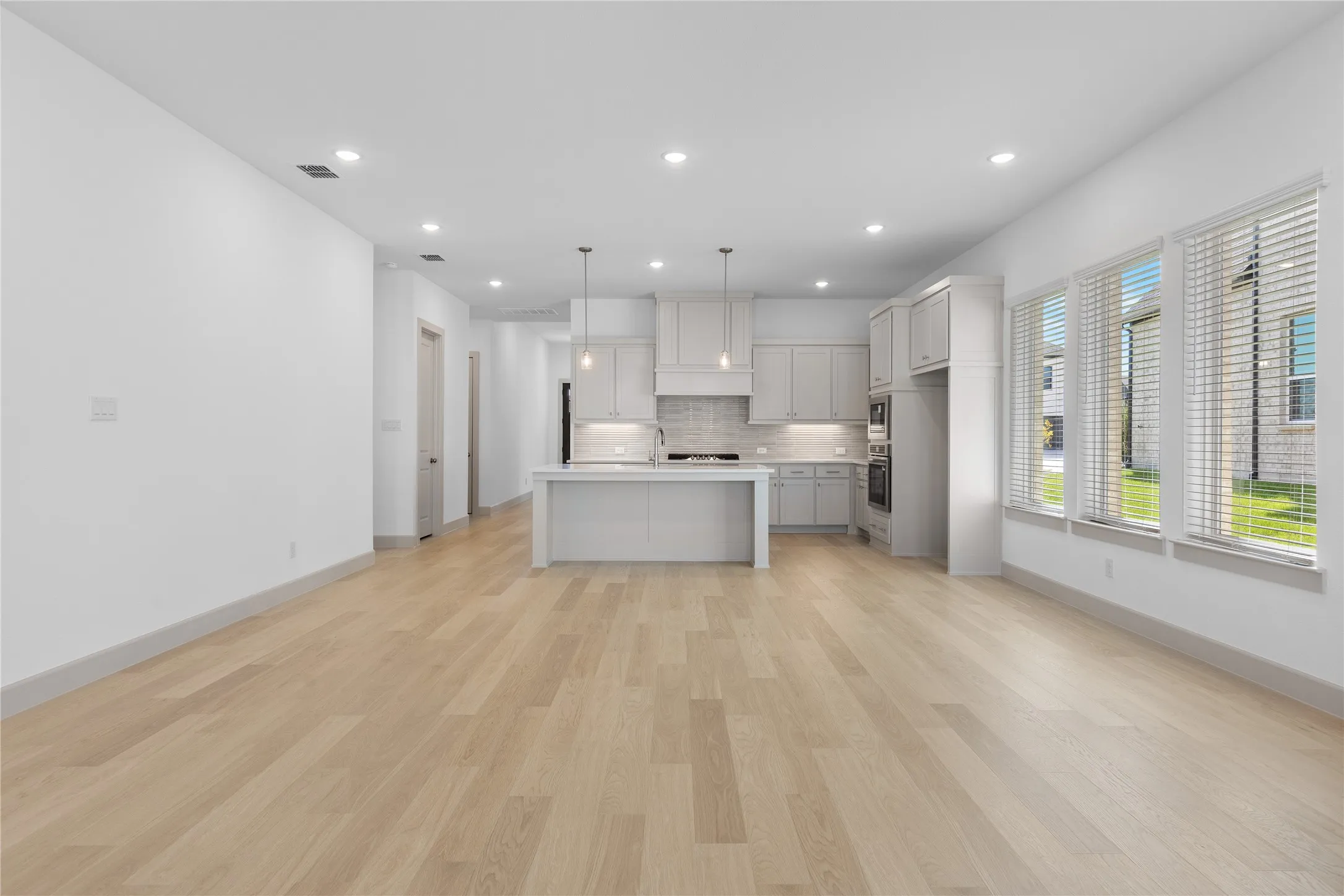 Open concept living area featuring wood-finish flooring, recessed lighting, and multiple windows