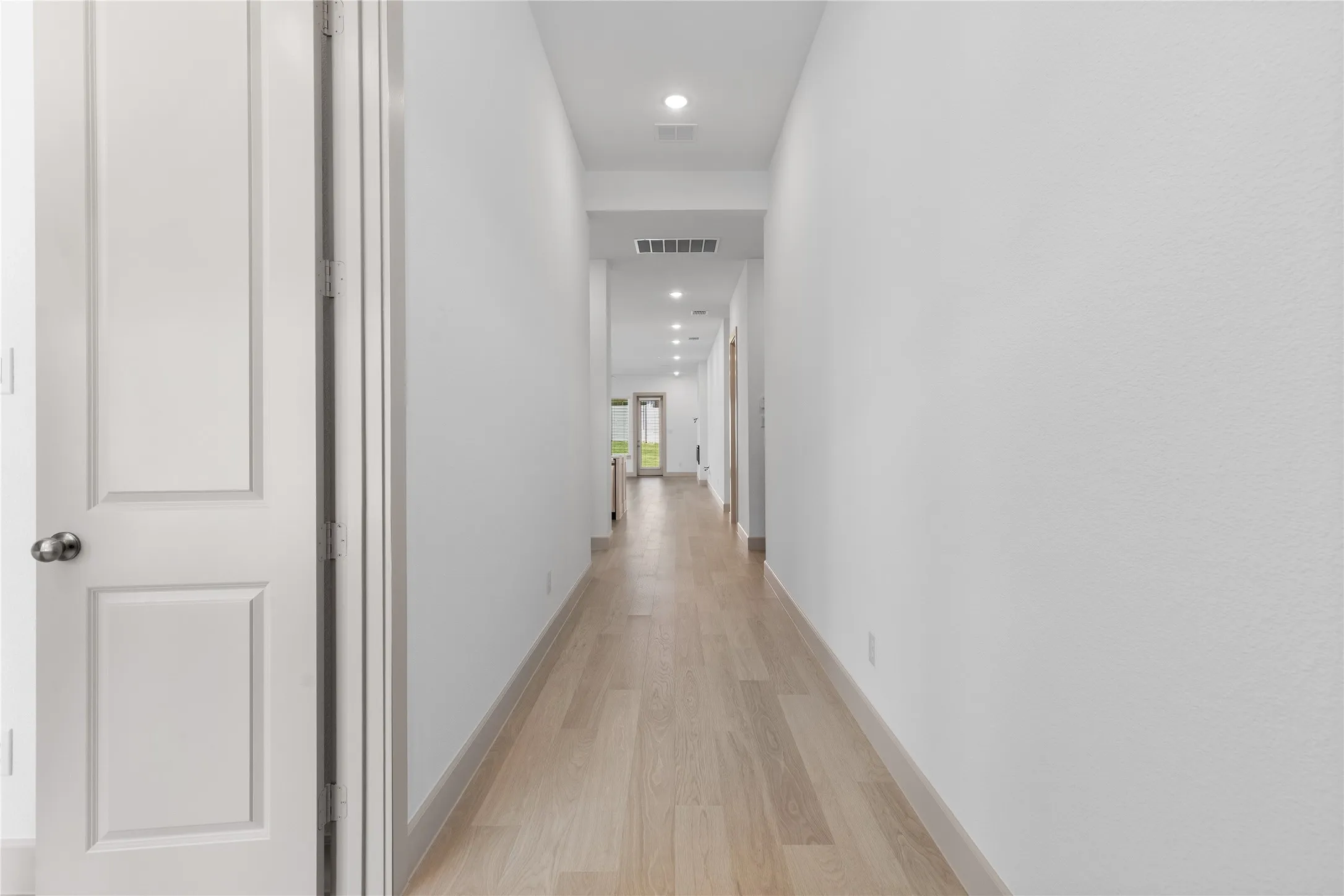 Light wood-finish flooring extending through the hallway