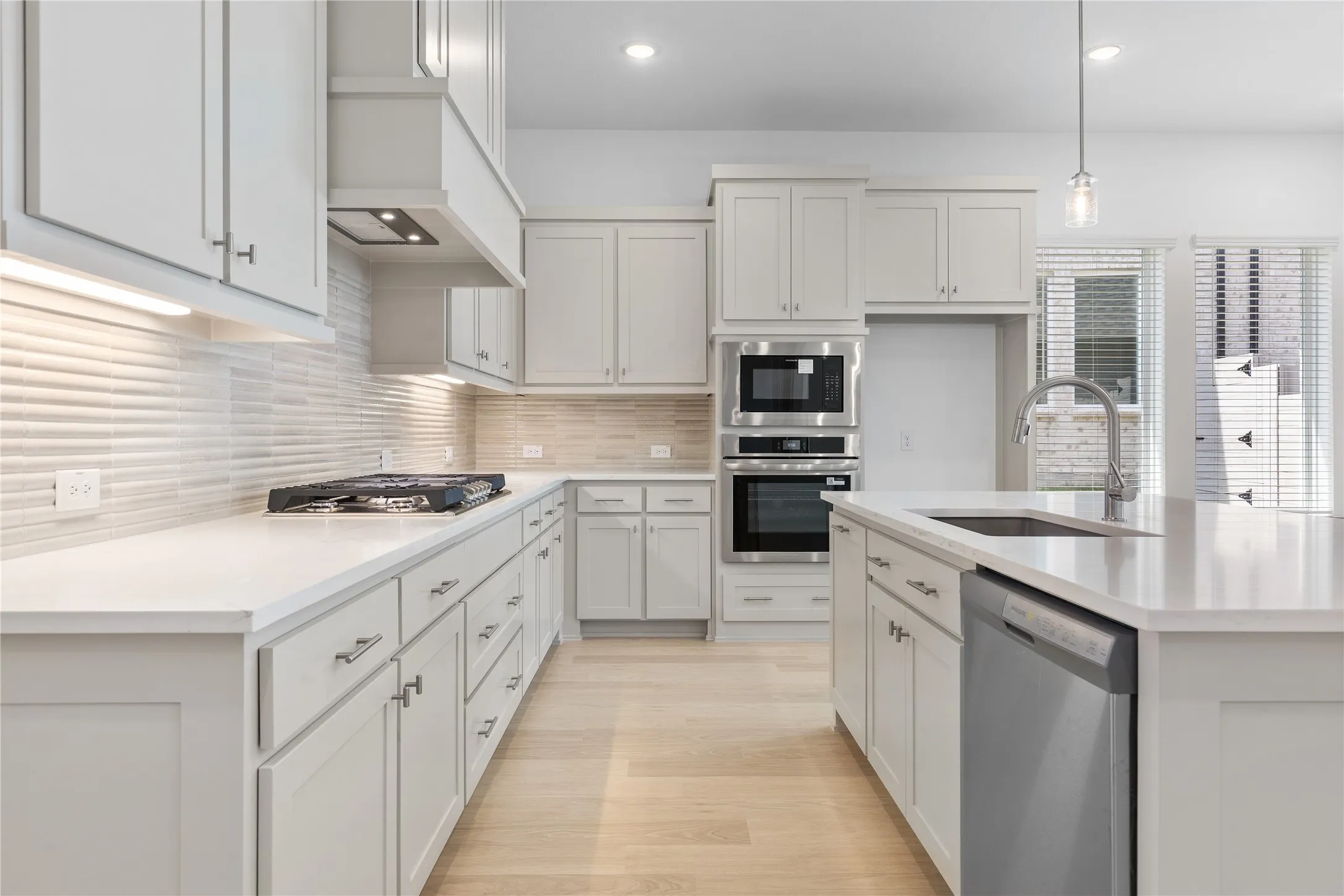 Kitchen featuring a gas cooktop, stainless steel appliances, a large island, and light wood-finish flooring