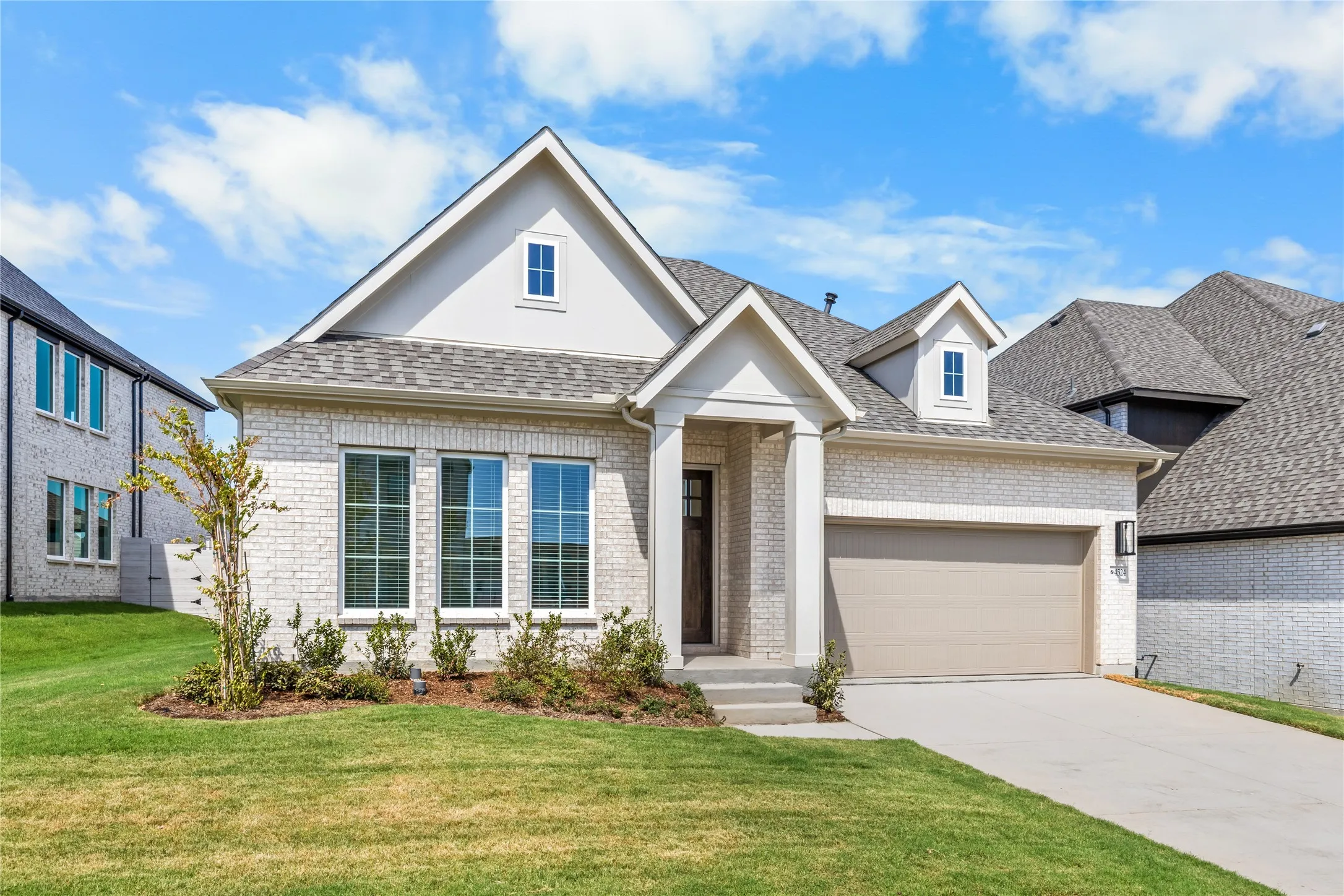 Light brick exterior with a pitched roof, front-facing gables, and a two-car garage