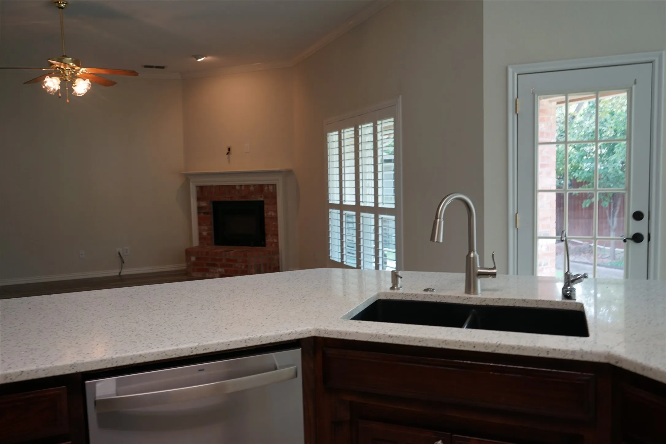 Kitchen island with a speckled countertop, undermount double-basin sink, and a stainless steel pull-down faucet
