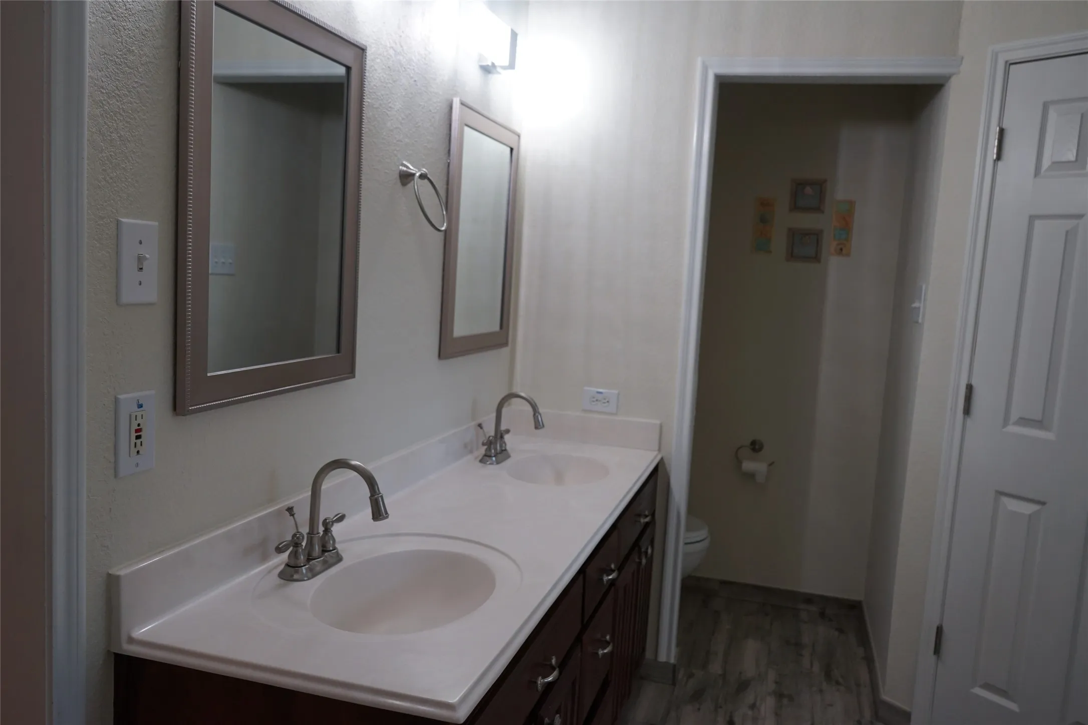 Dual basin vanity with a light-toned countertop and wood-finish cabinetry