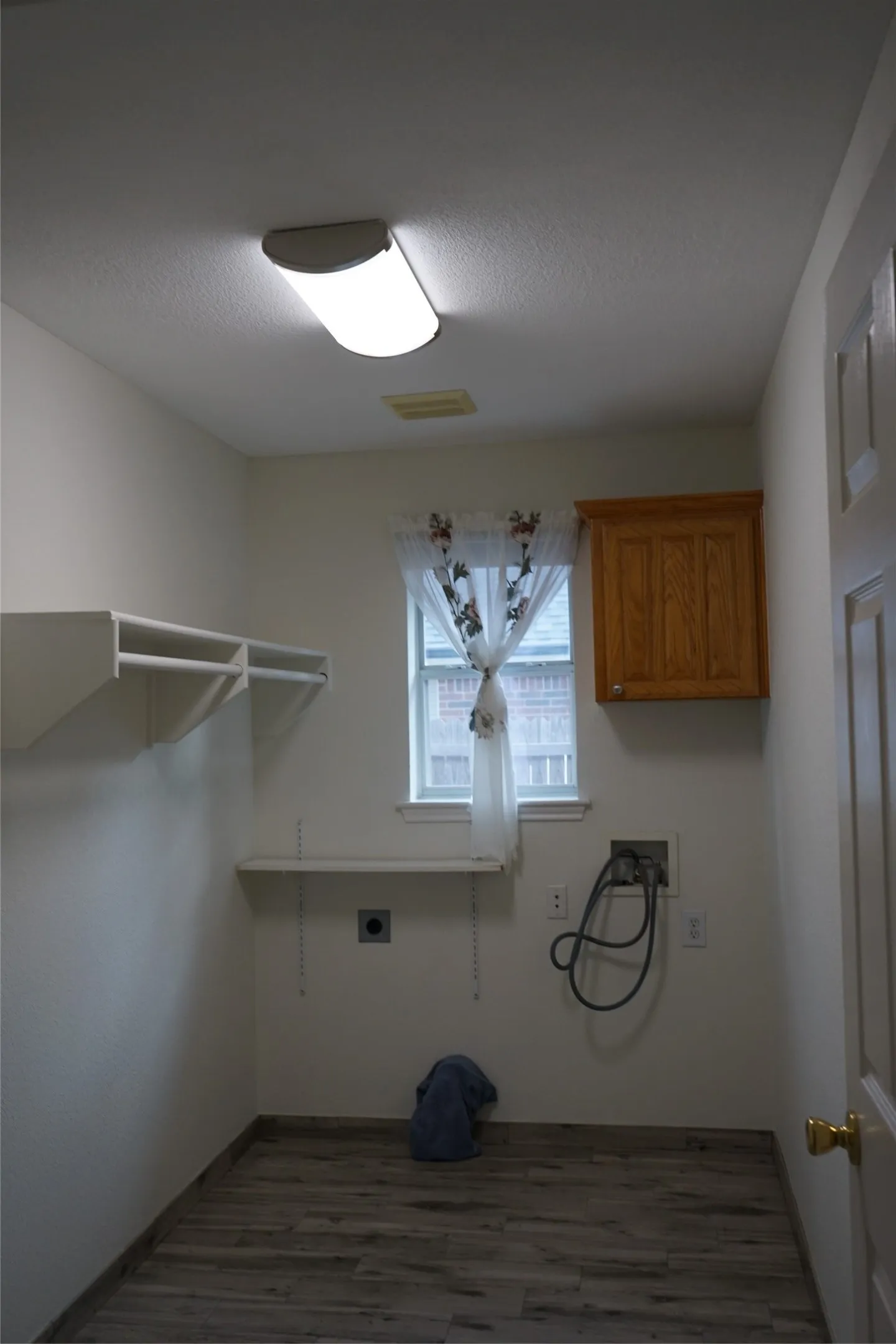 Room with wood-finish flooring, built-in shelving, and a single window