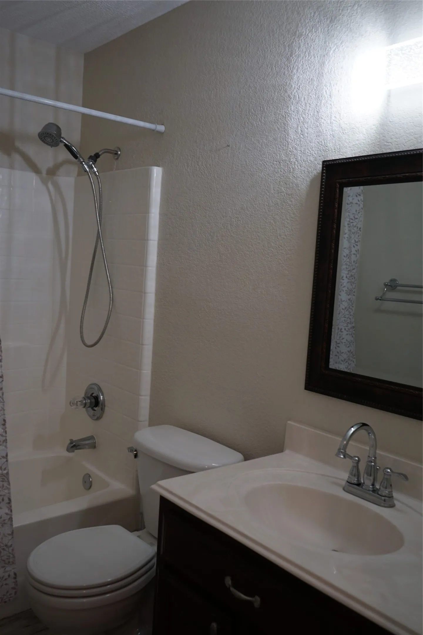 Vanity with dark wood-finish cabinetry, integrated sink, and chrome faucet