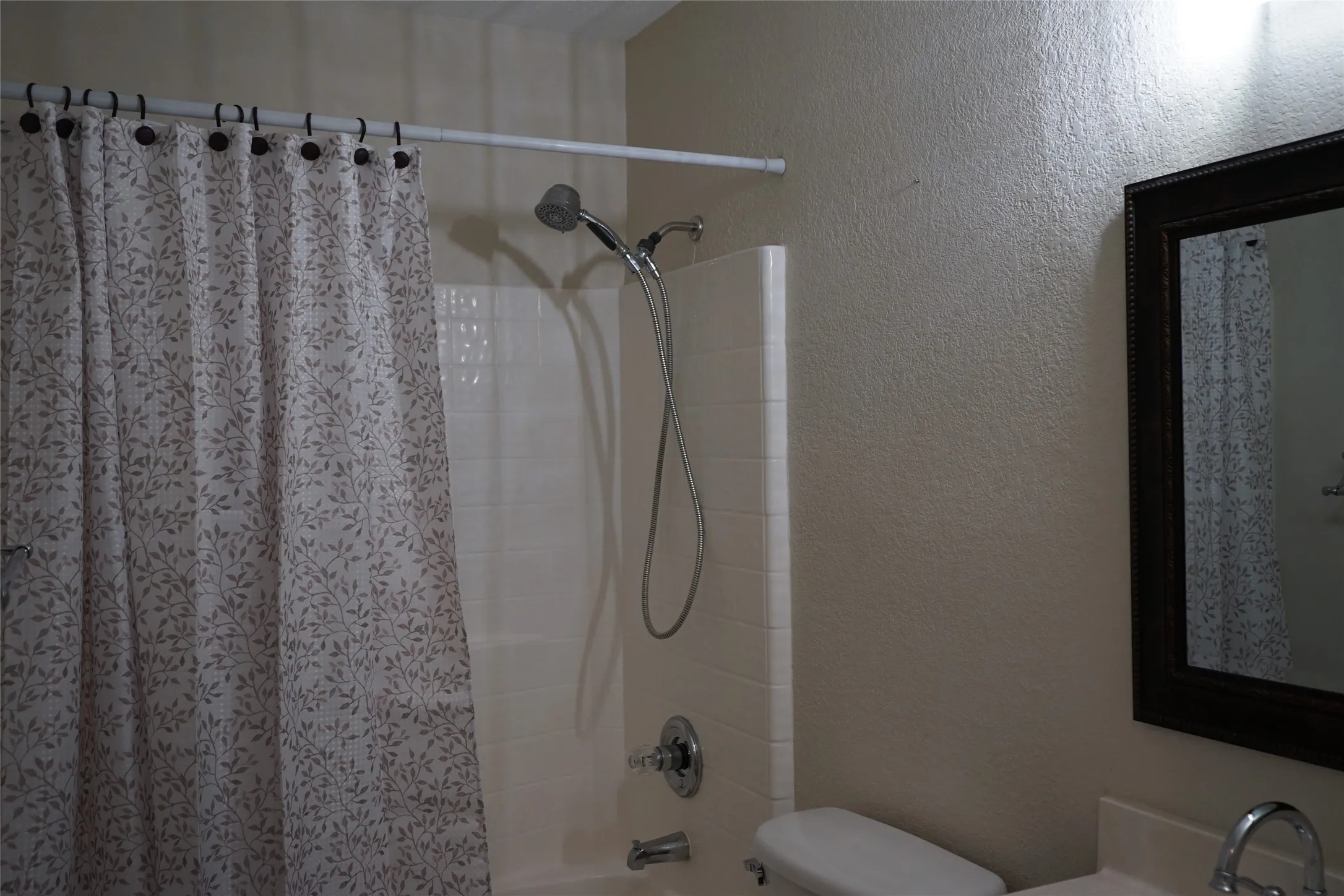 Bathtub shower combination with white tile surround and chrome fixtures