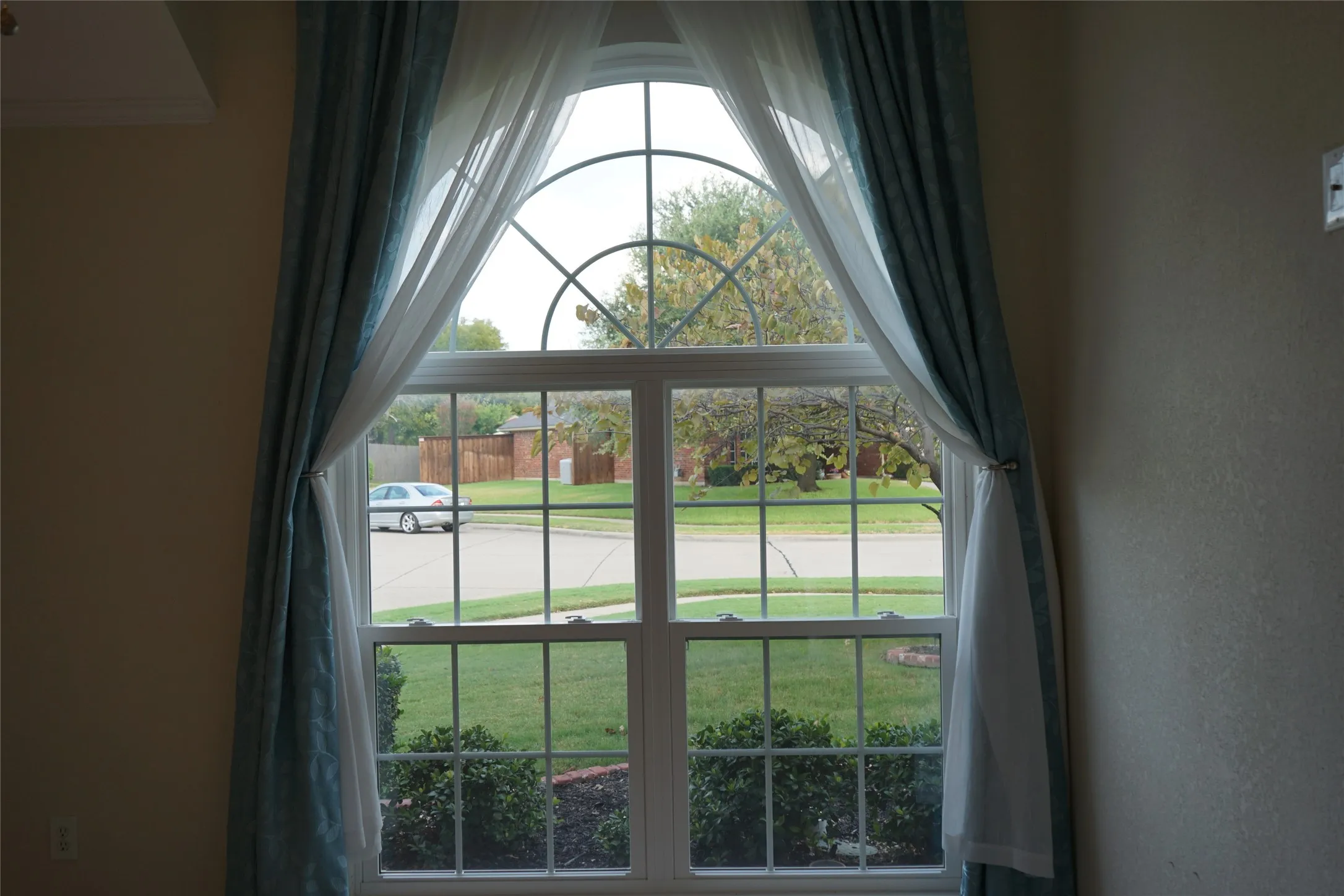 Arched window with gridded panes, interior wall with a neutral finish, and crown molding