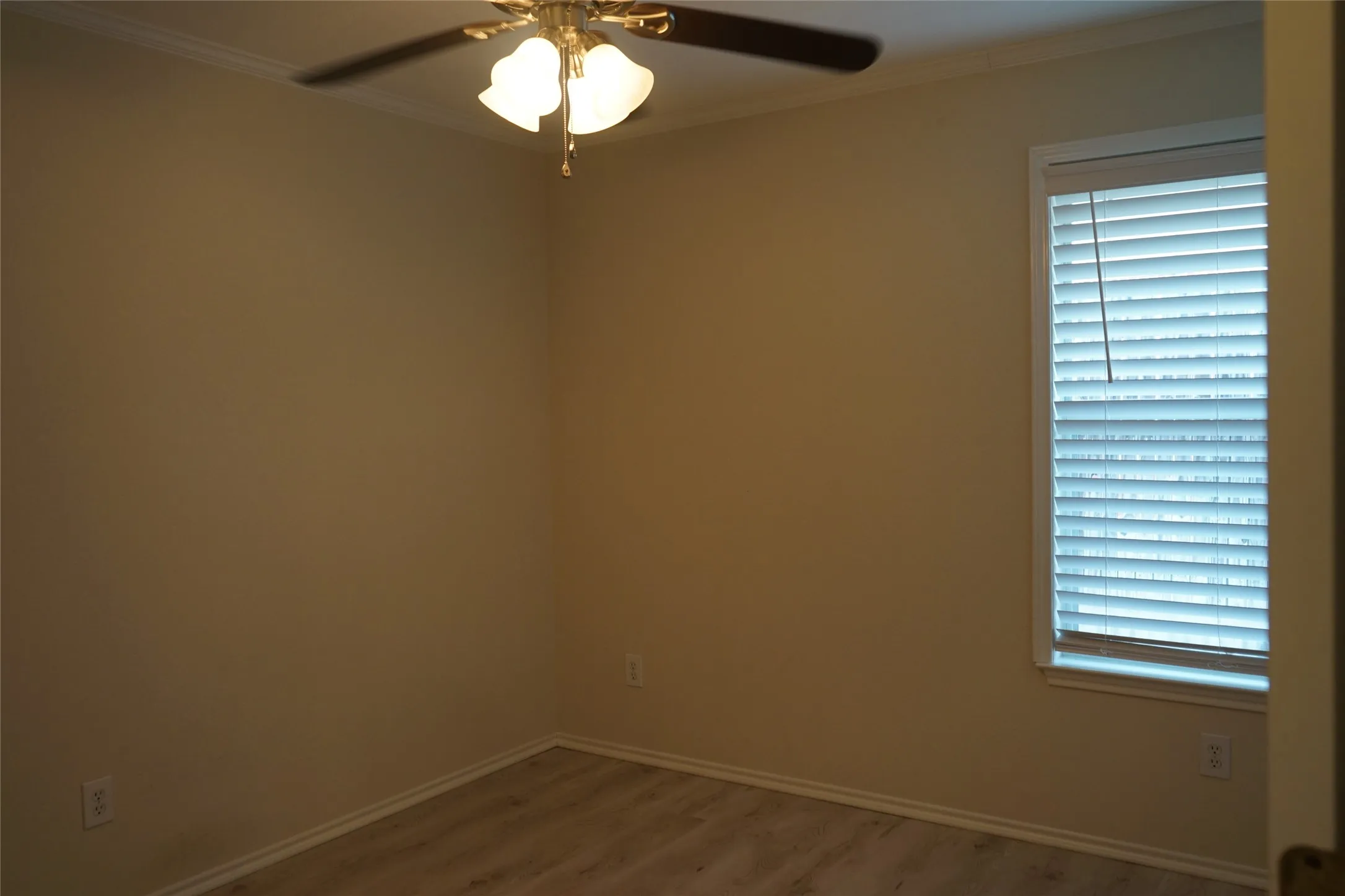 Light wood-finish flooring, ceiling fan with integrated lighting, and window with blinds