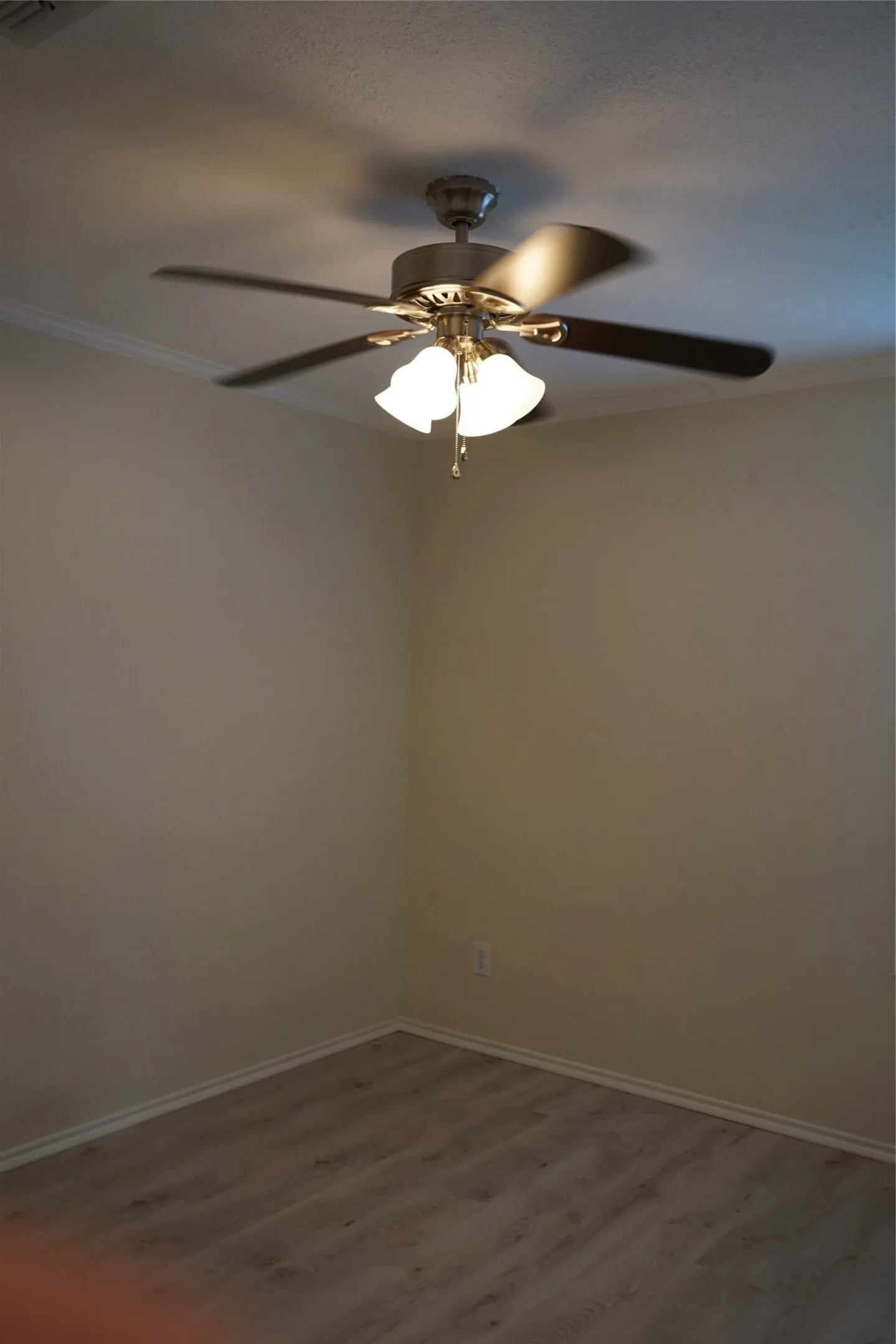 Ceiling fan with integrated lighting, wood-finish flooring, and crown molding