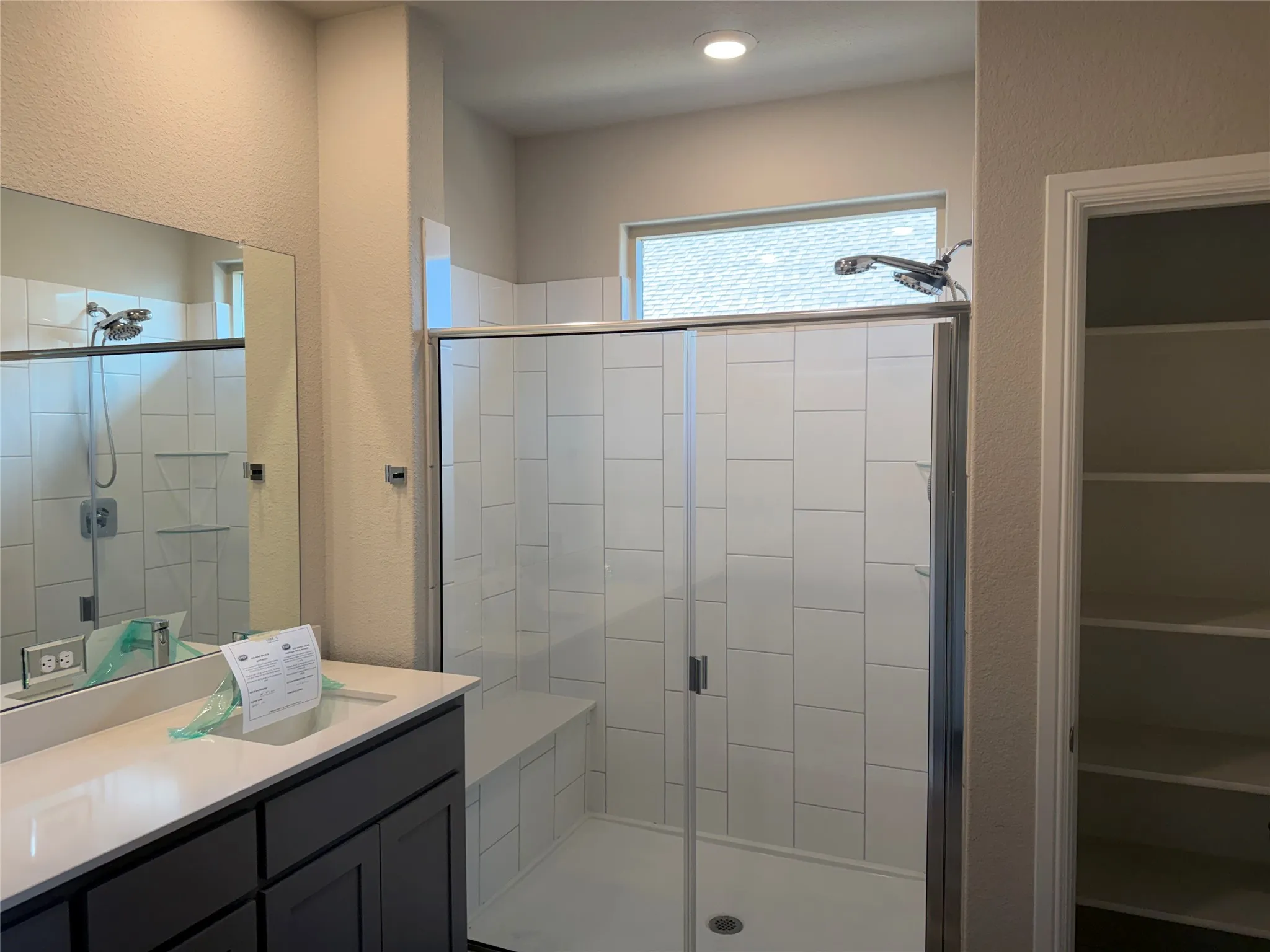 Walk-in shower with white subway tile, built-in shower bench, glass enclosure, and transom window