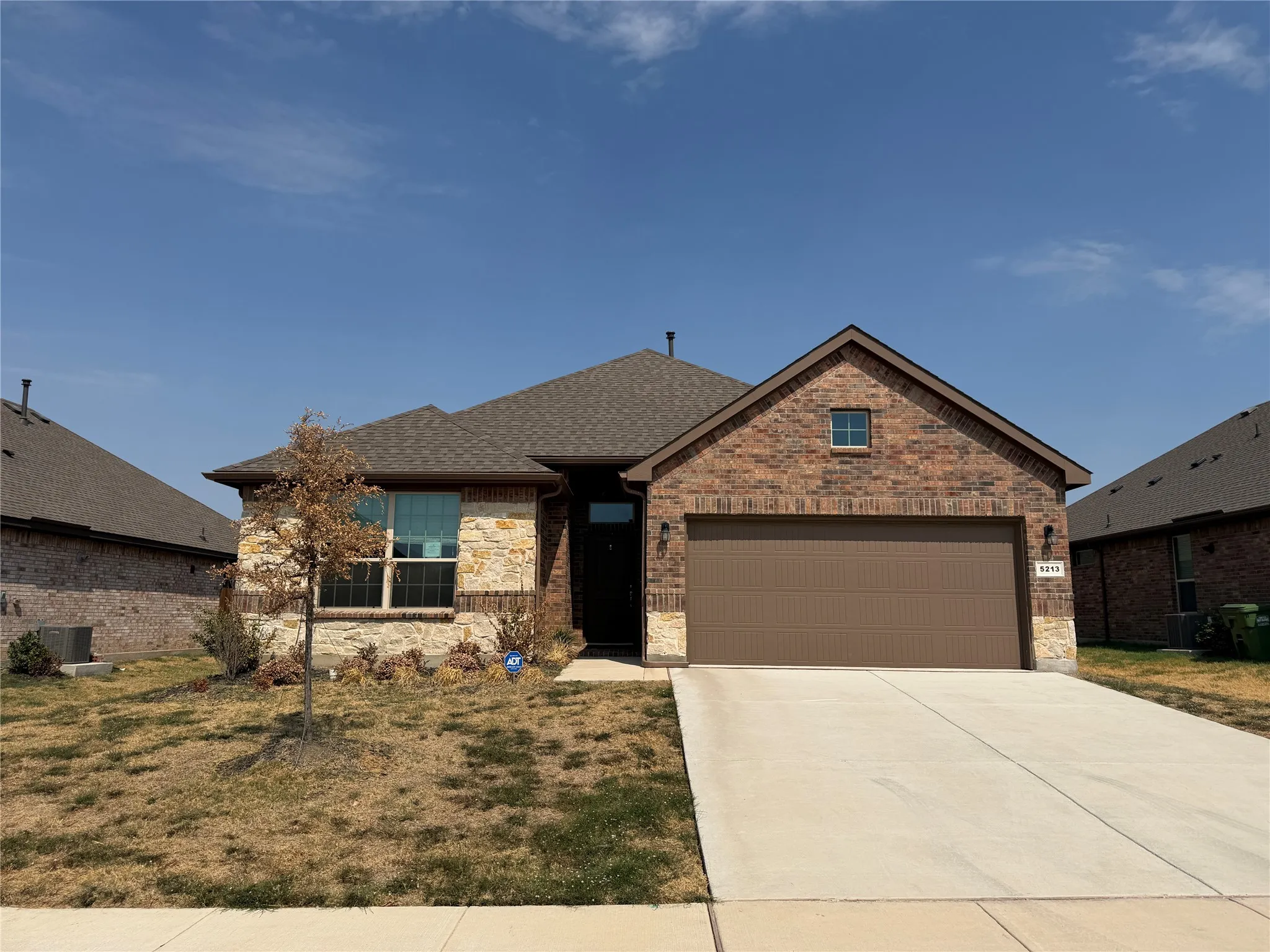 Brick and stone veneer facade, covered entry, attached two-car garage, concrete driveway, and a gabled roofline