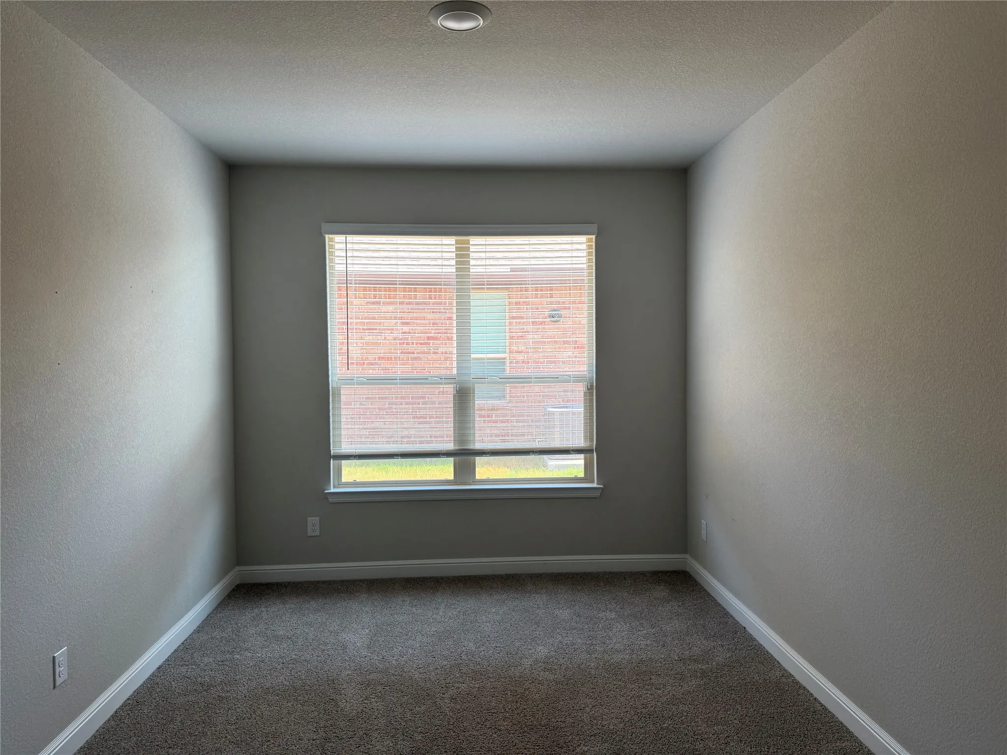 Recessed ceiling light fixture, neutral wall color, white window trim, horizontal window blinds, and gray carpet