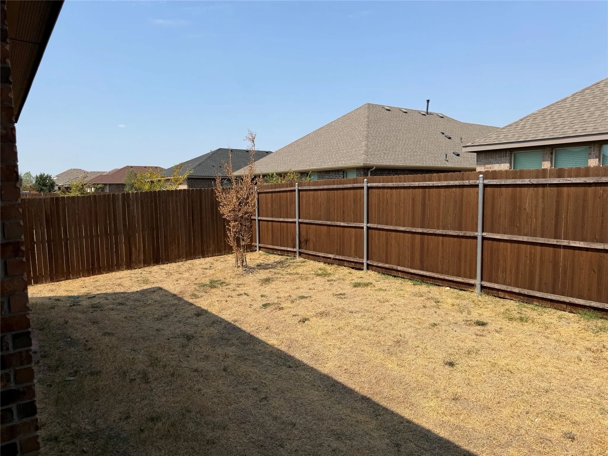 Enclosed backyard featuring a wood privacy fence with metal posts