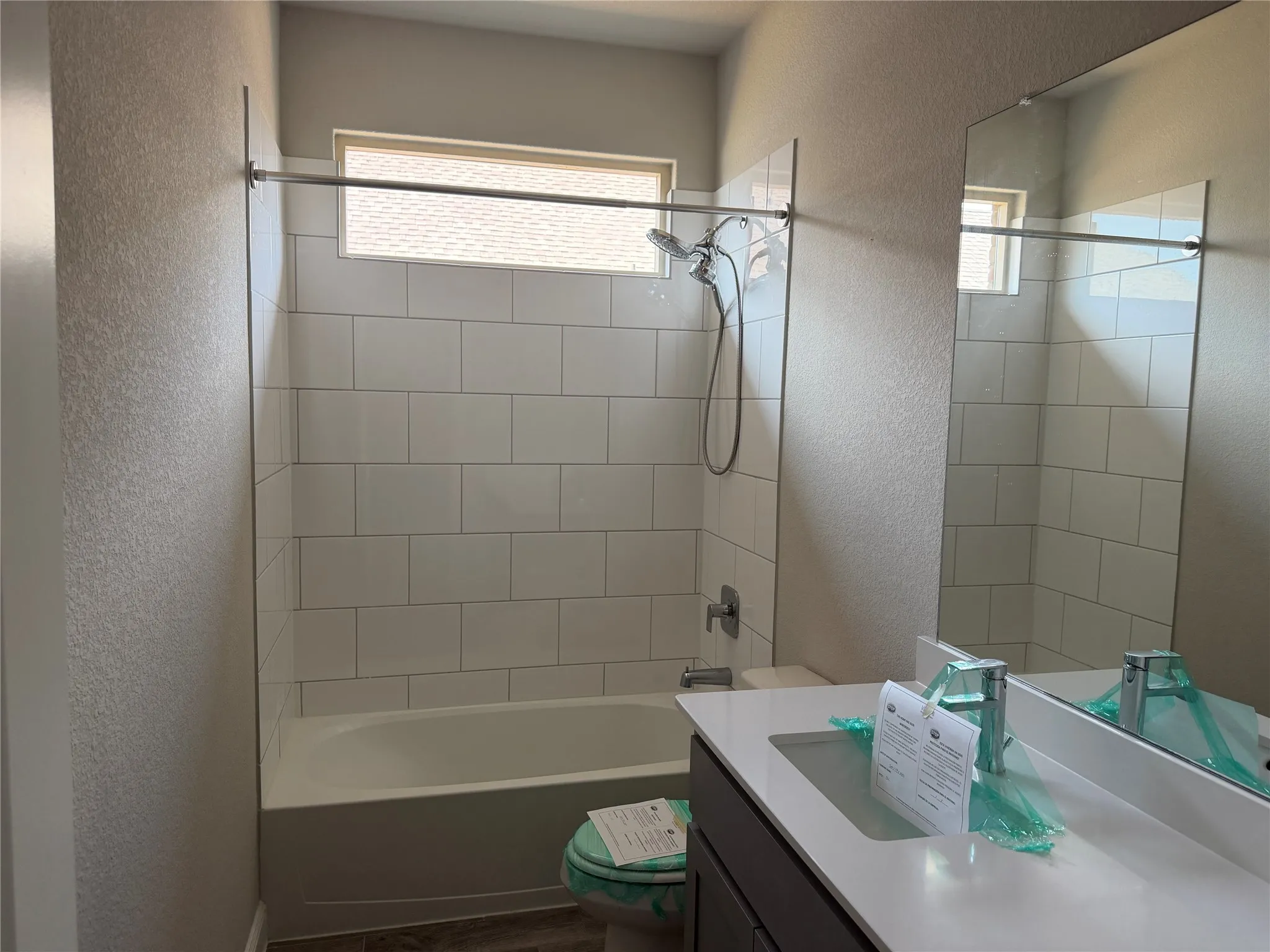 Bathtub with subway tile surround, chrome shower fixtures, and a transom window