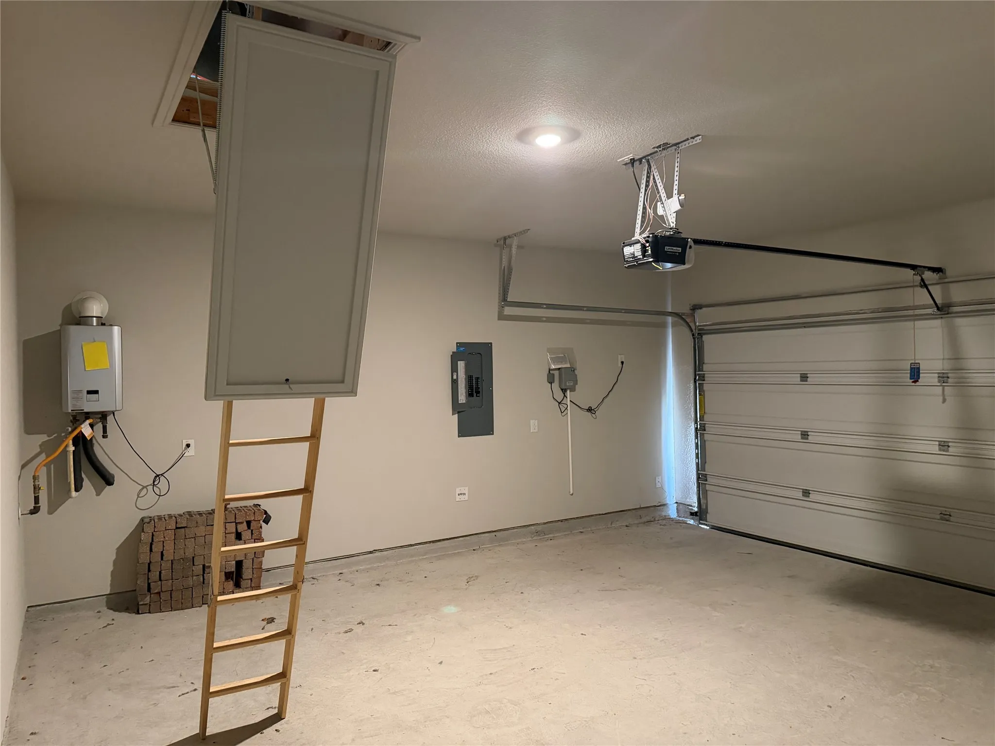 Garage with a concrete floor, overhead door, and a wall-mounted water heater