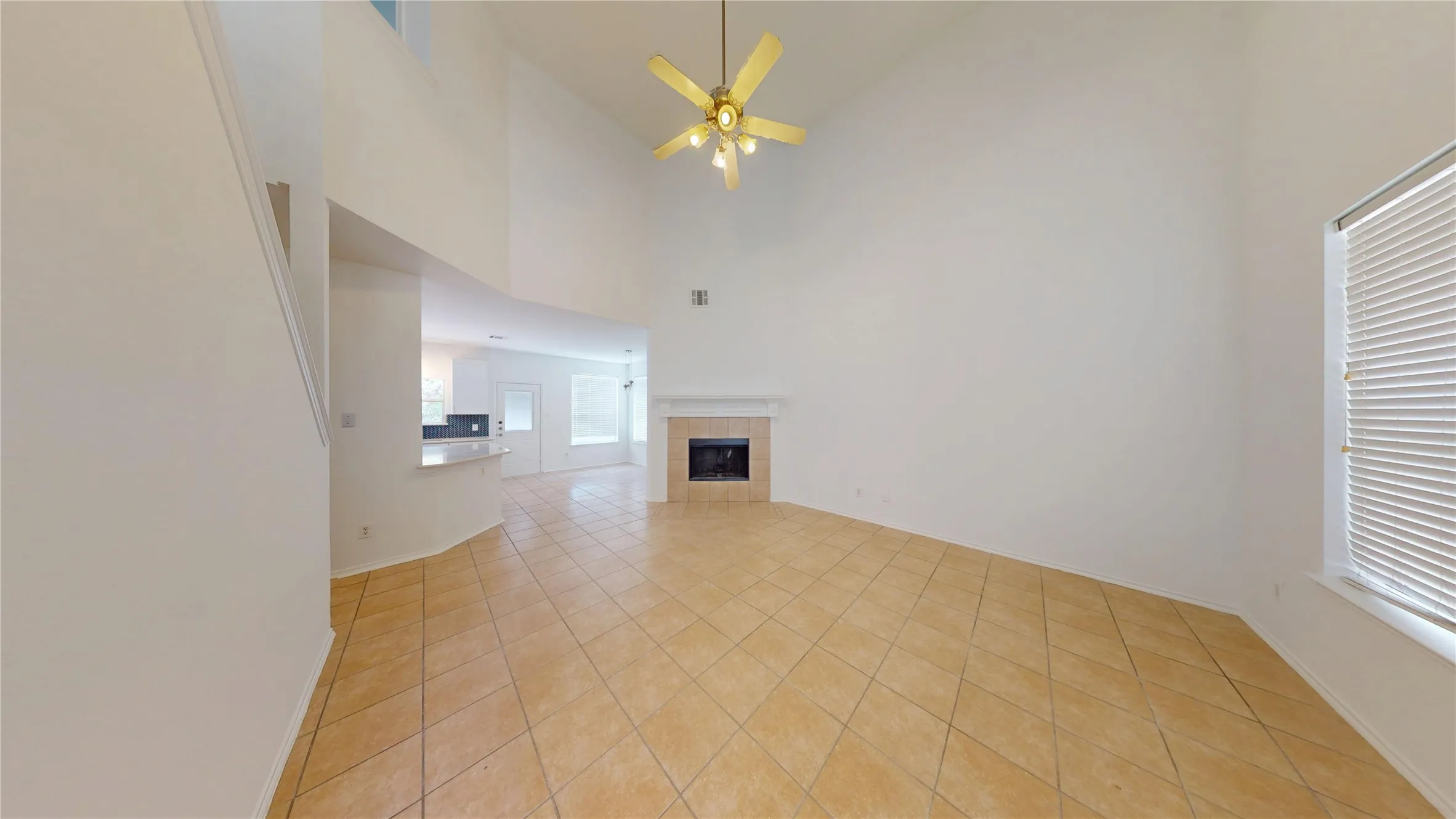 Vaulted ceiling, ceiling fan, fireplace with mantel, window with blinds, and tile flooring