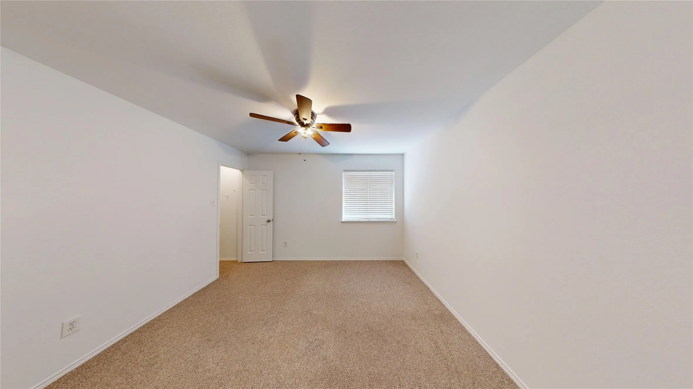 Recessed window with blinds, ceiling-mounted fan with integrated lighting, carpeted flooring, and a white interior door