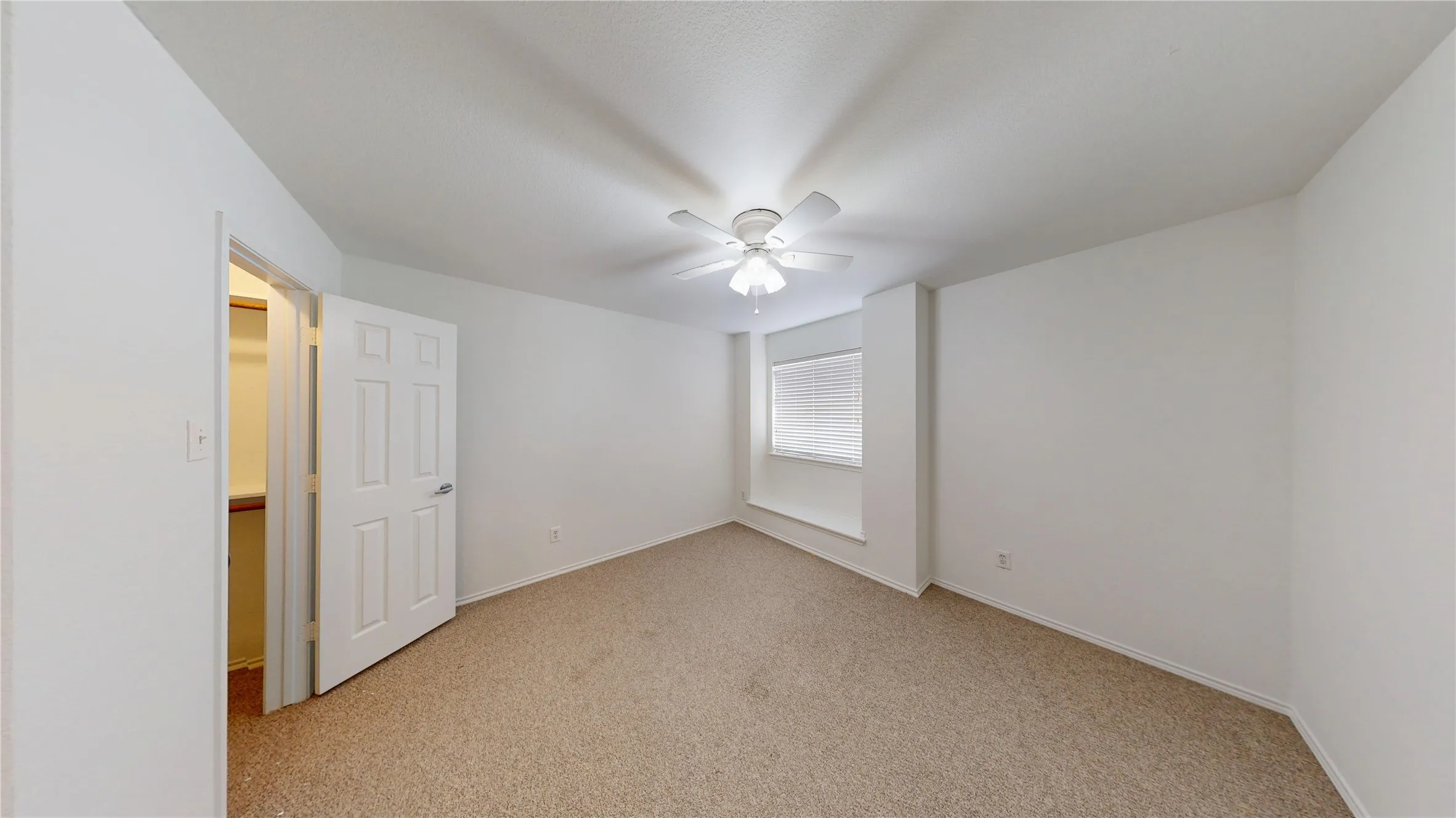 Carpeted room featuring a ceiling fan with integrated lighting, a window with blinds, and a built-in window ledge