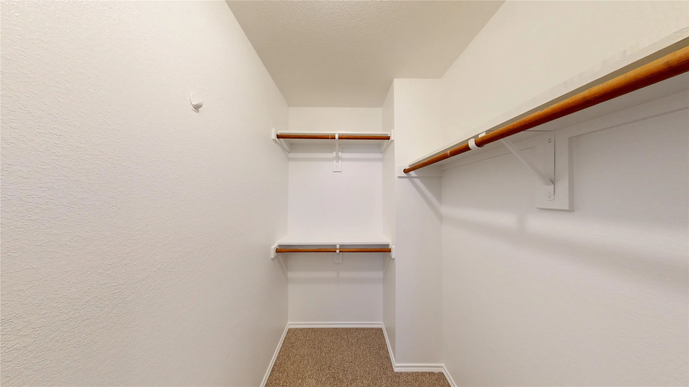 Built-in shelving with hanging rods and carpet flooring