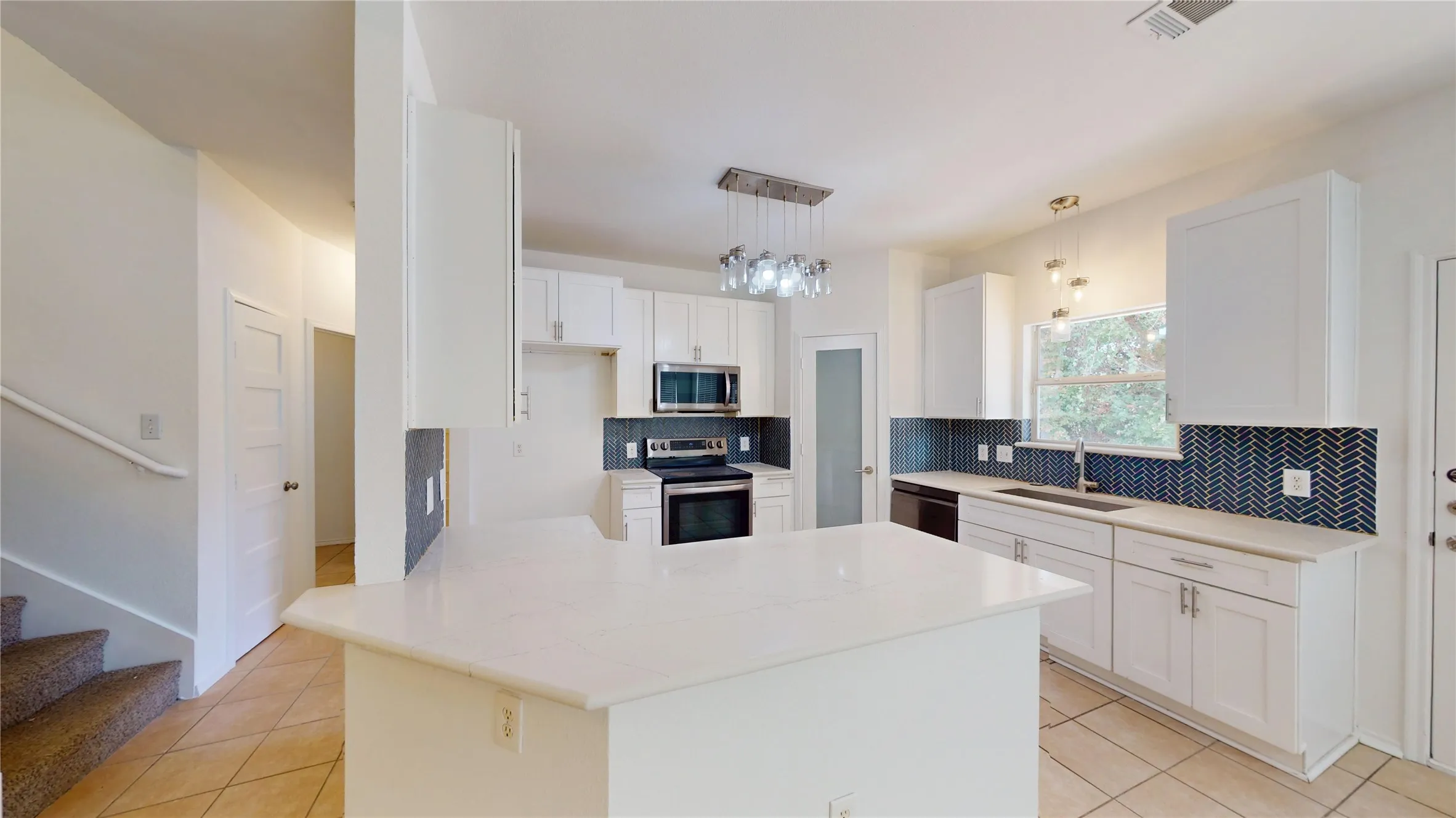 Kitchen featuring white shaker cabinetry, white countertops, stainless steel appliances, and a blue herringbone tile backsplash
