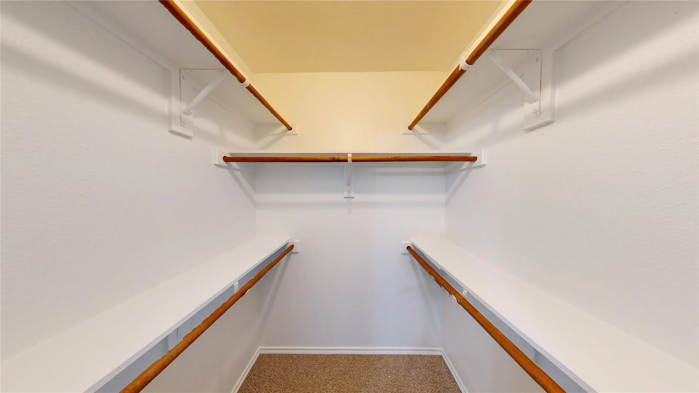 Built-in closet shelving, integrated hanging rods, and carpet flooring