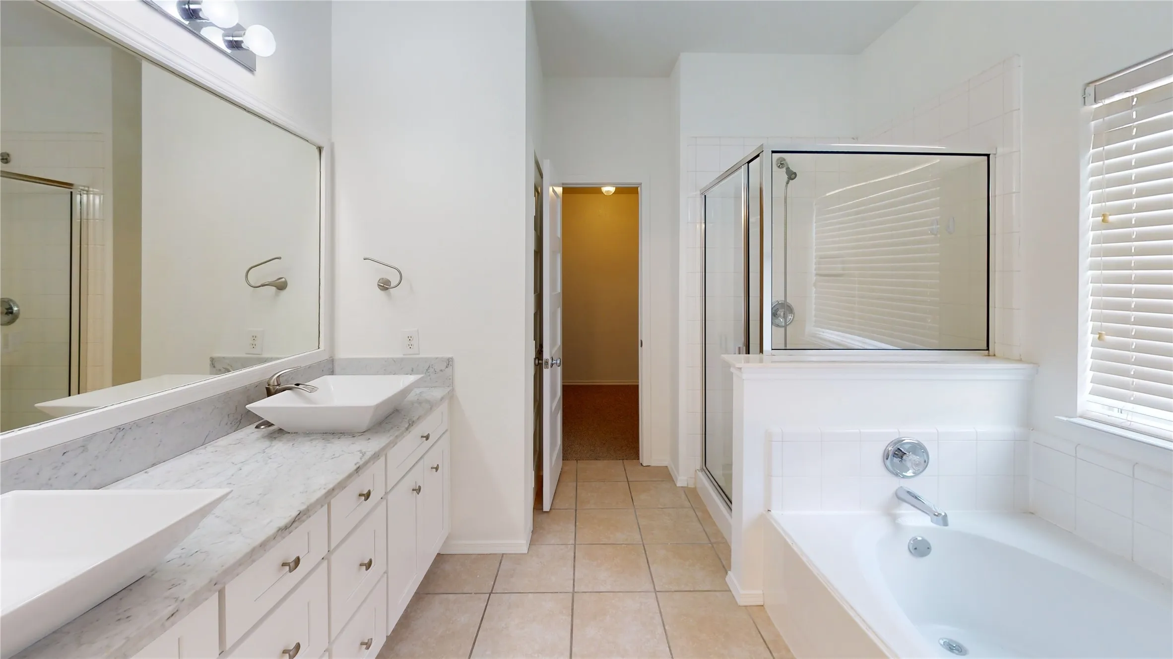 Dual vanity with vessel sinks, tiled flooring, glass-enclosed shower, and built-in bathtub