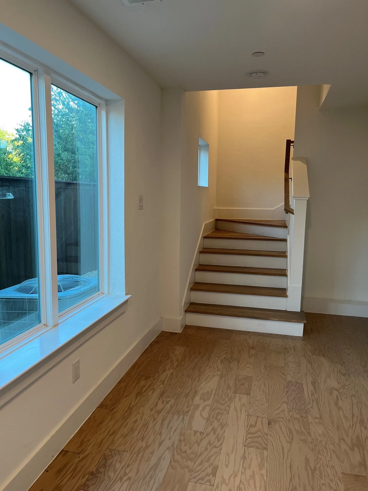 Wood-finish flooring, white trim, staircase with wood treads, and a large window