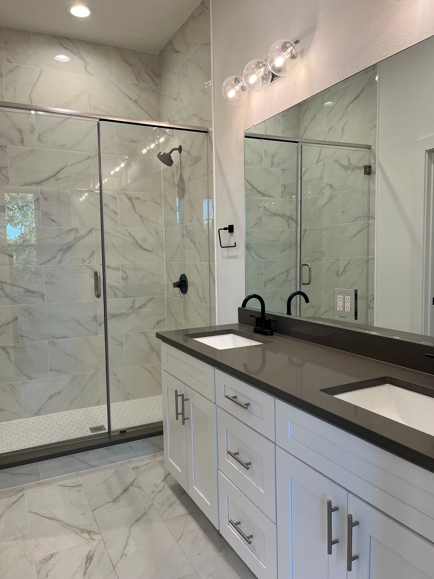 Double vanity in Primatry bathroom with white cabinetry, dark countertops, and matte black fixtures