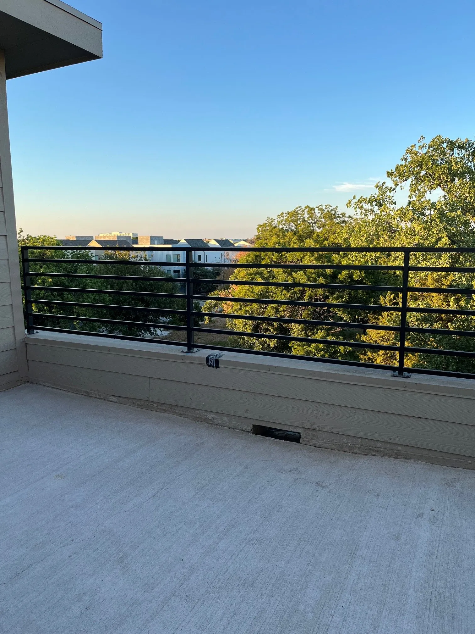 Rooftop terrace with concrete surface and a black horizontal bar railing