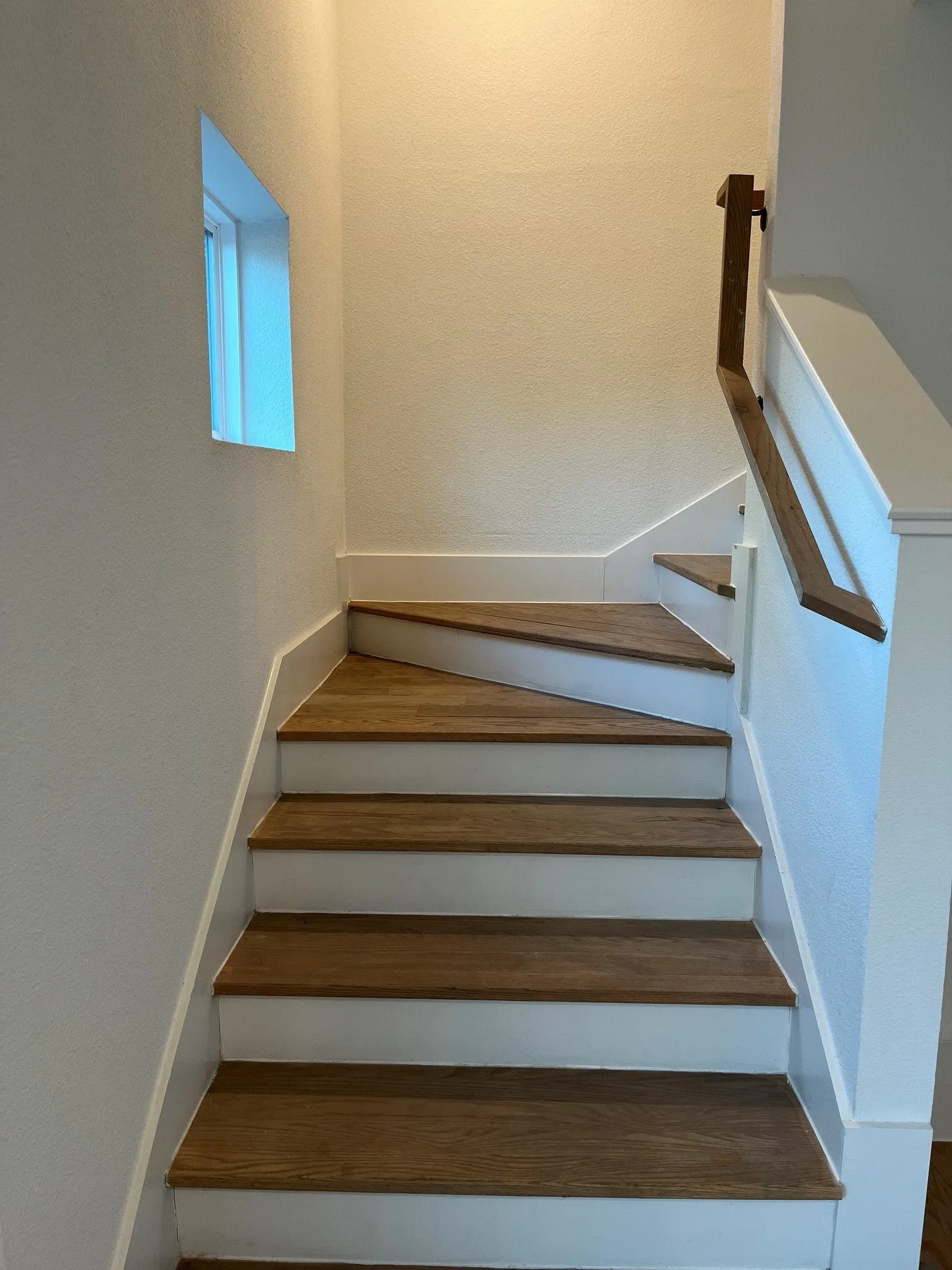 Staircase leading to second level featuring wood-finish treads, white risers, and a built-in window
