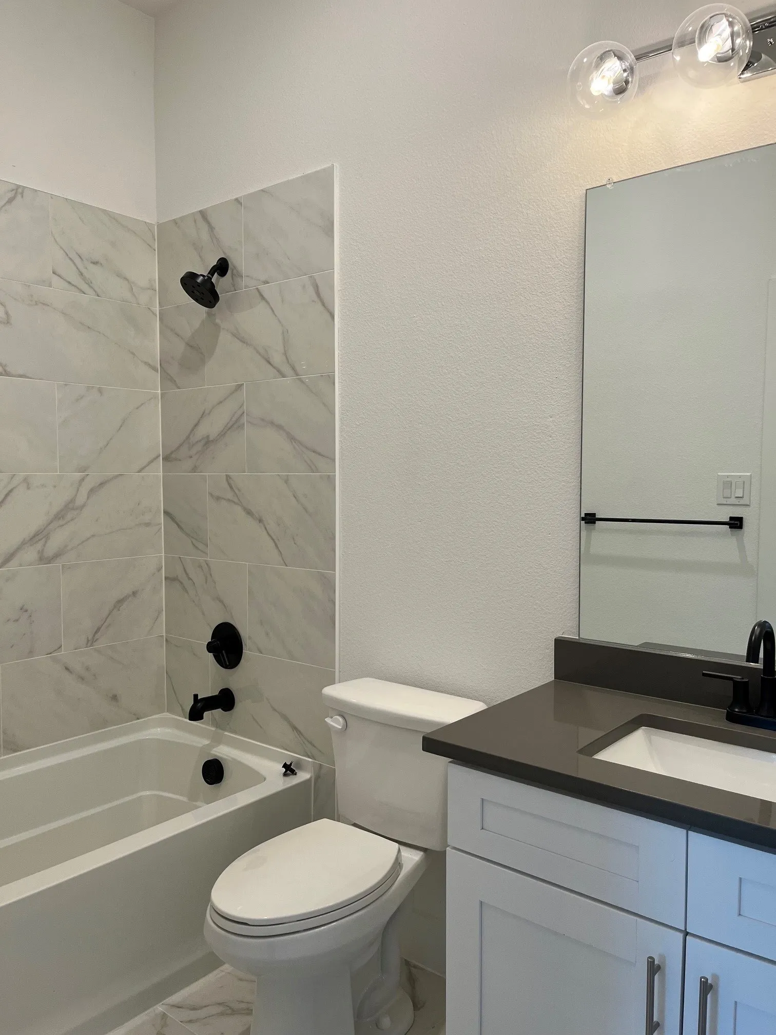 Ensuite Bathroom featuring a full vanity with a rectangular sink, dark countertop, and matte black fixtures