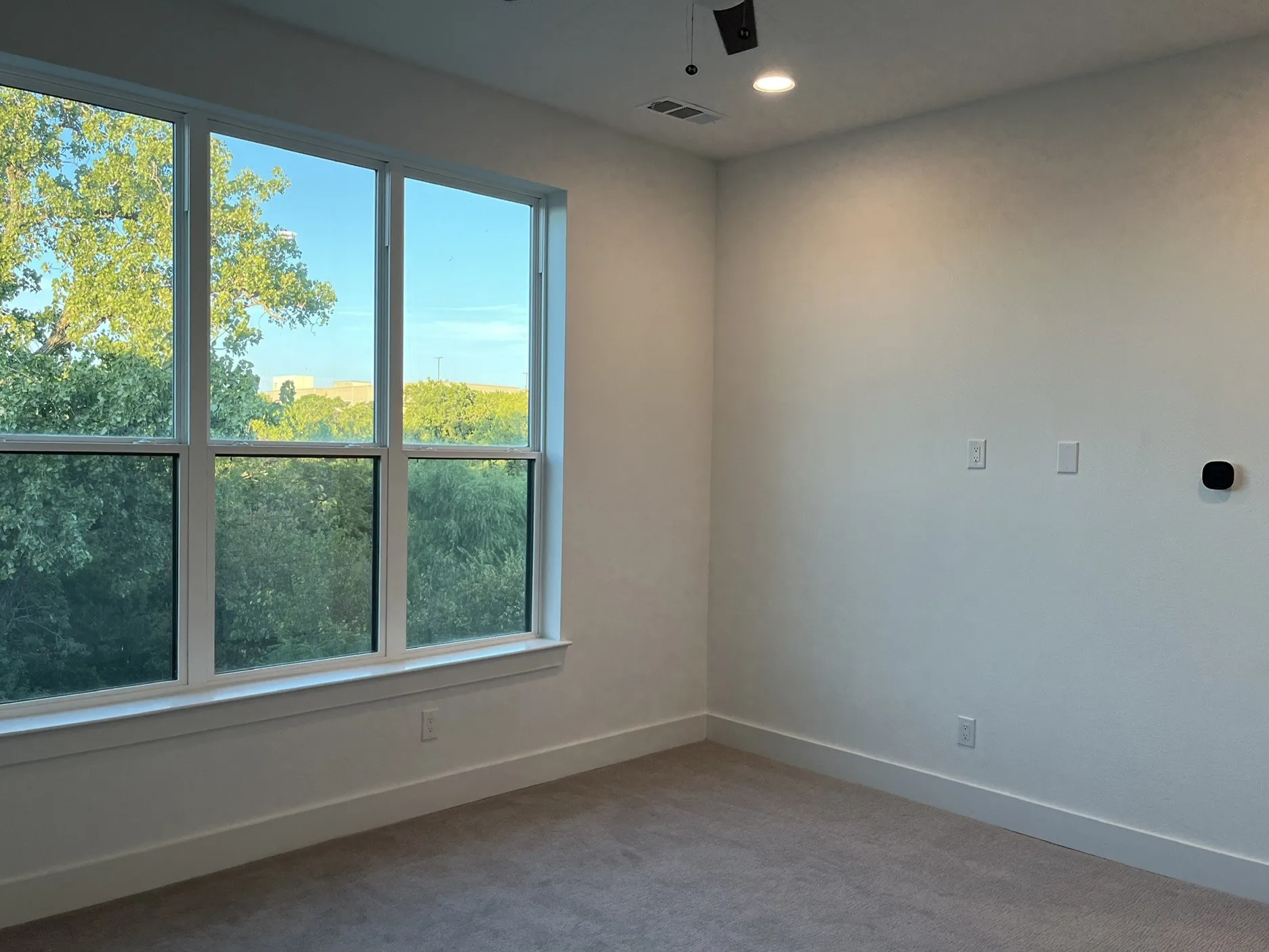 Large picture window in Primary Bedroom, recessed ceiling lighting, light neutral wall tones, clean-lined trim work, and carpeted flooring