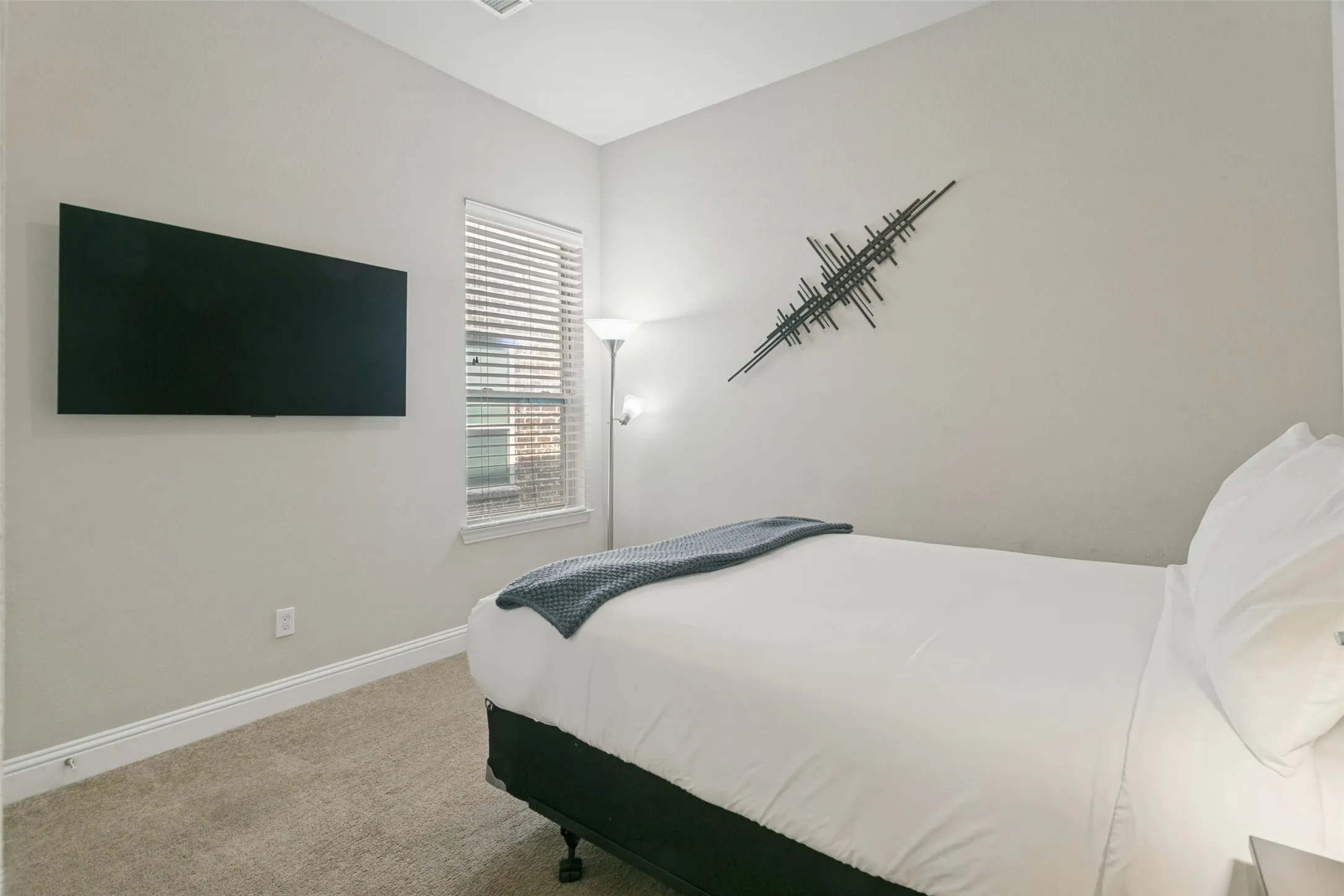 Wall-mounted television with a window featuring horizontal blinds