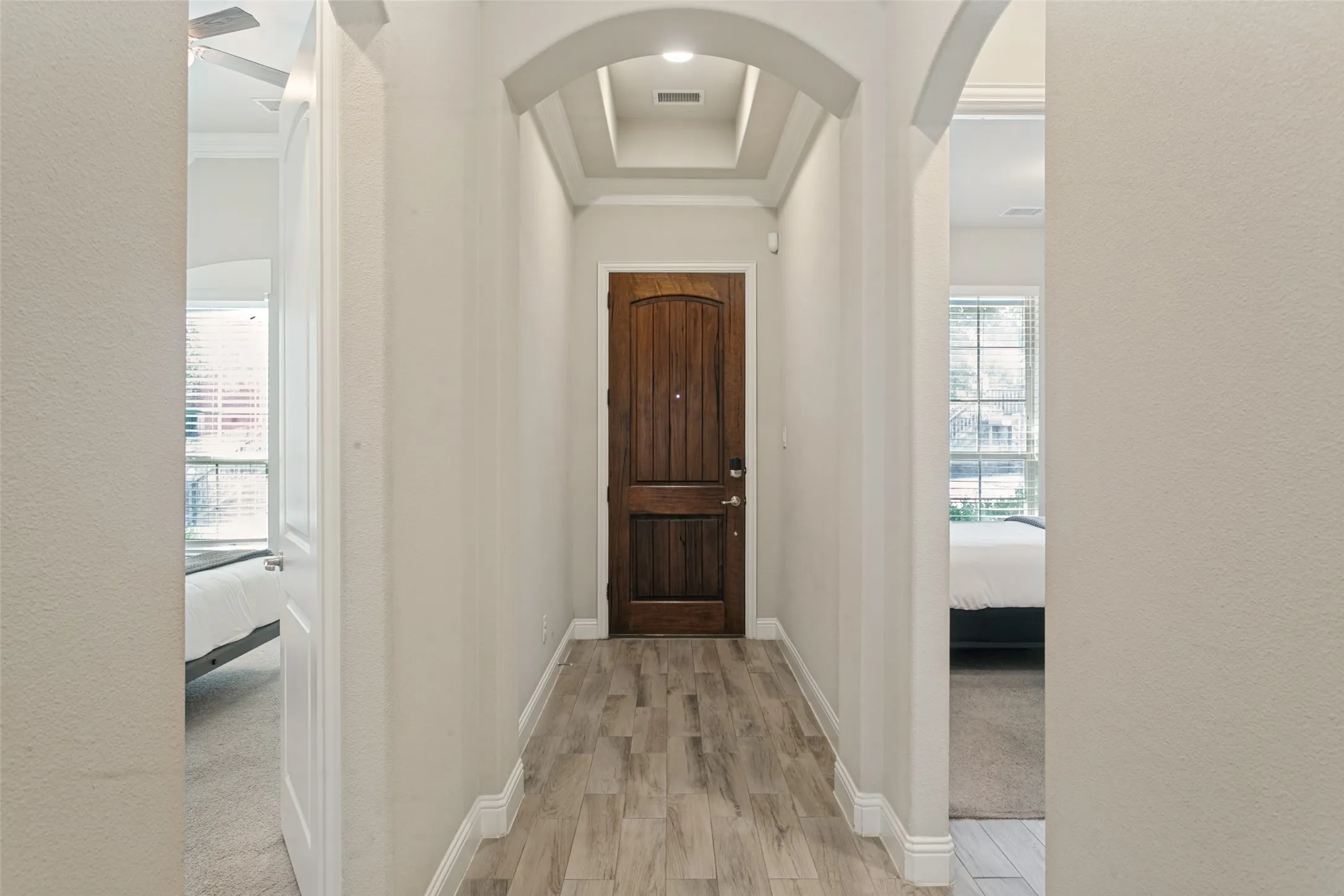 Arched entryway with a coffered ceiling, wood-finish flooring, and a paneled wood entry door